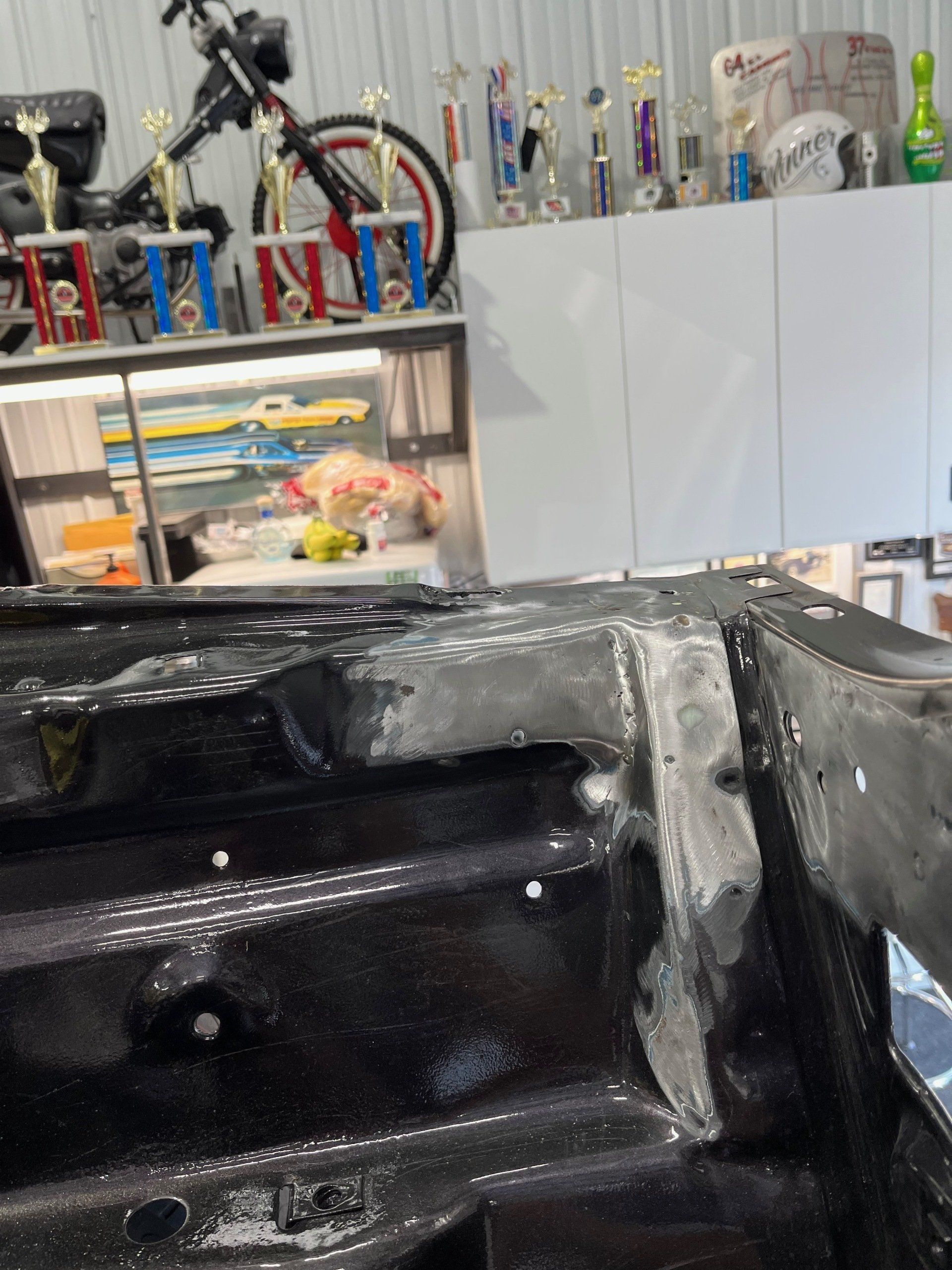 Black painted car interior in a workshop, with shelves of tools and supplies in the background