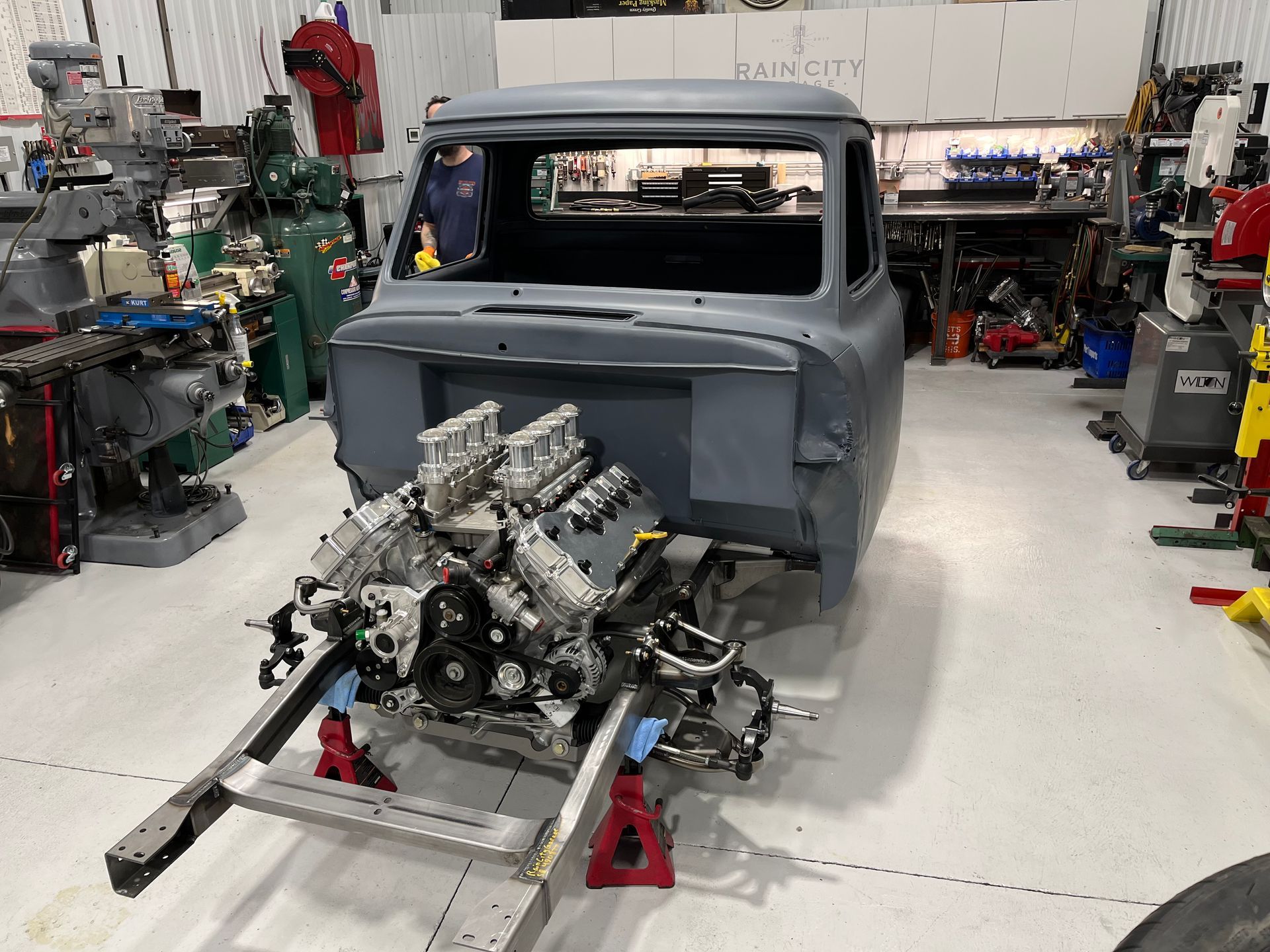 Classic truck cab in a workshop, with engine and chassis partially assembled on a dolly.