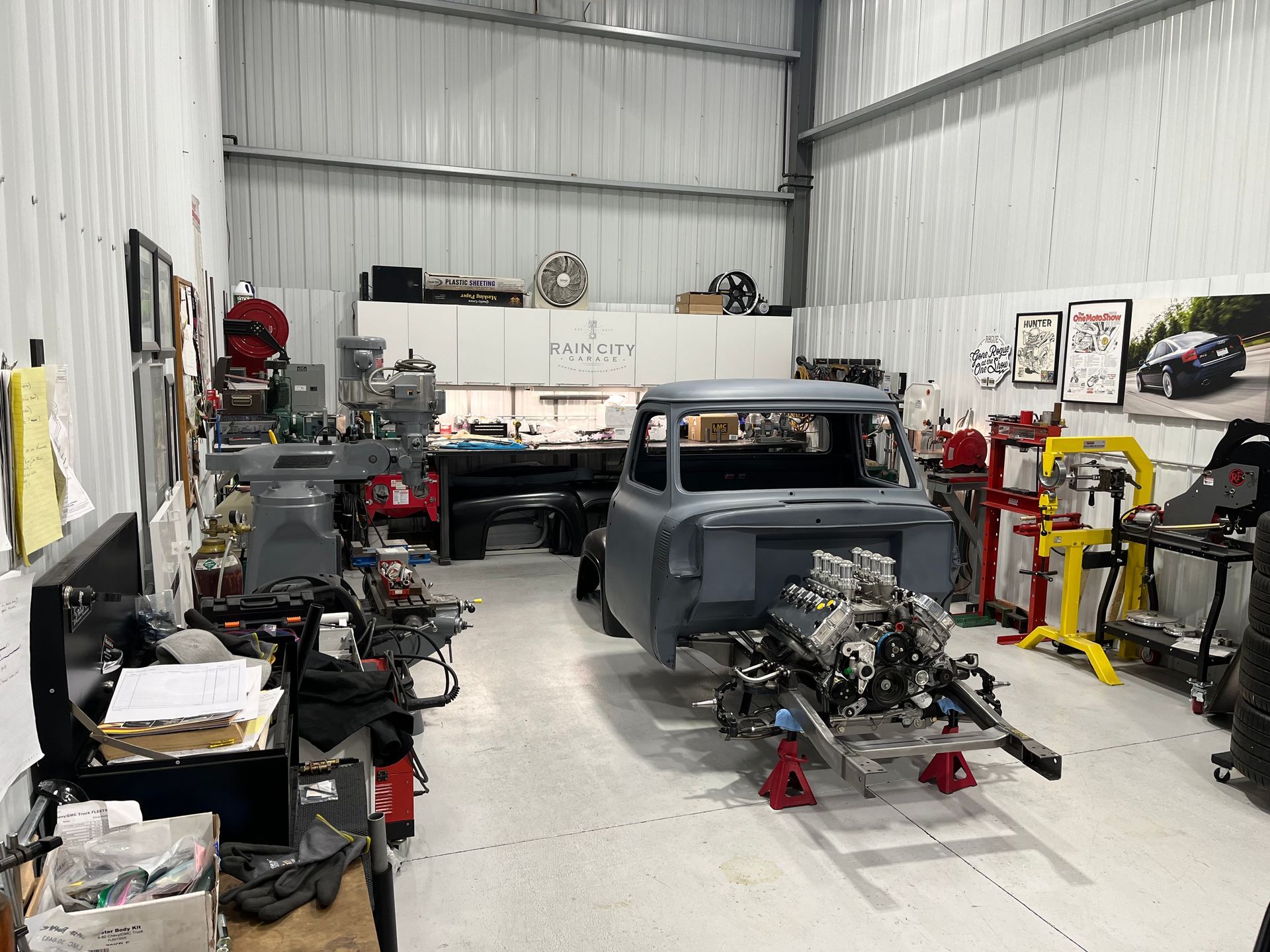 Auto repair garage with a partly restored classic truck, engine removed, and tools along the walls.