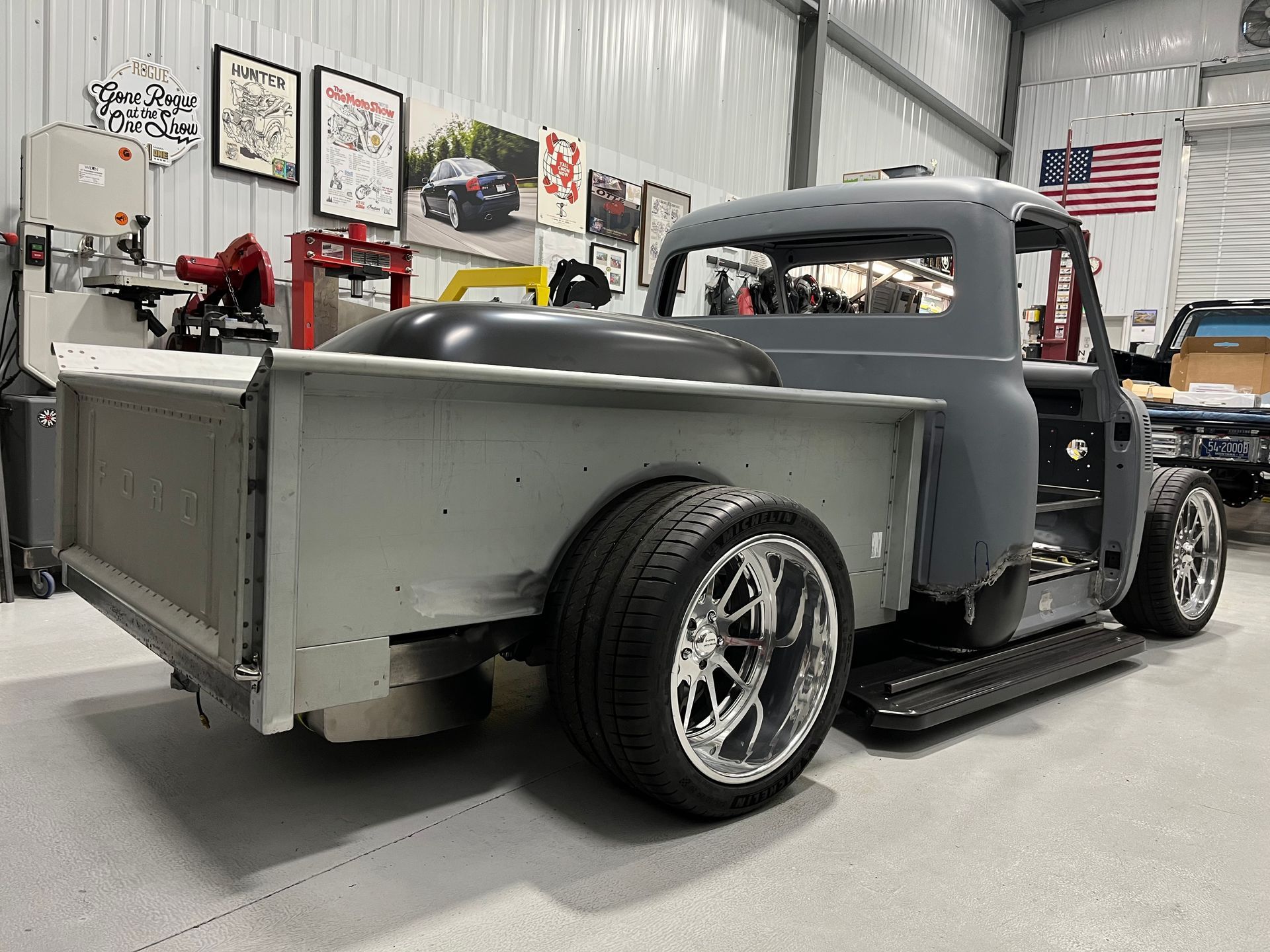 Gray custom vintage pickup truck in a garage, viewed from the rear side.