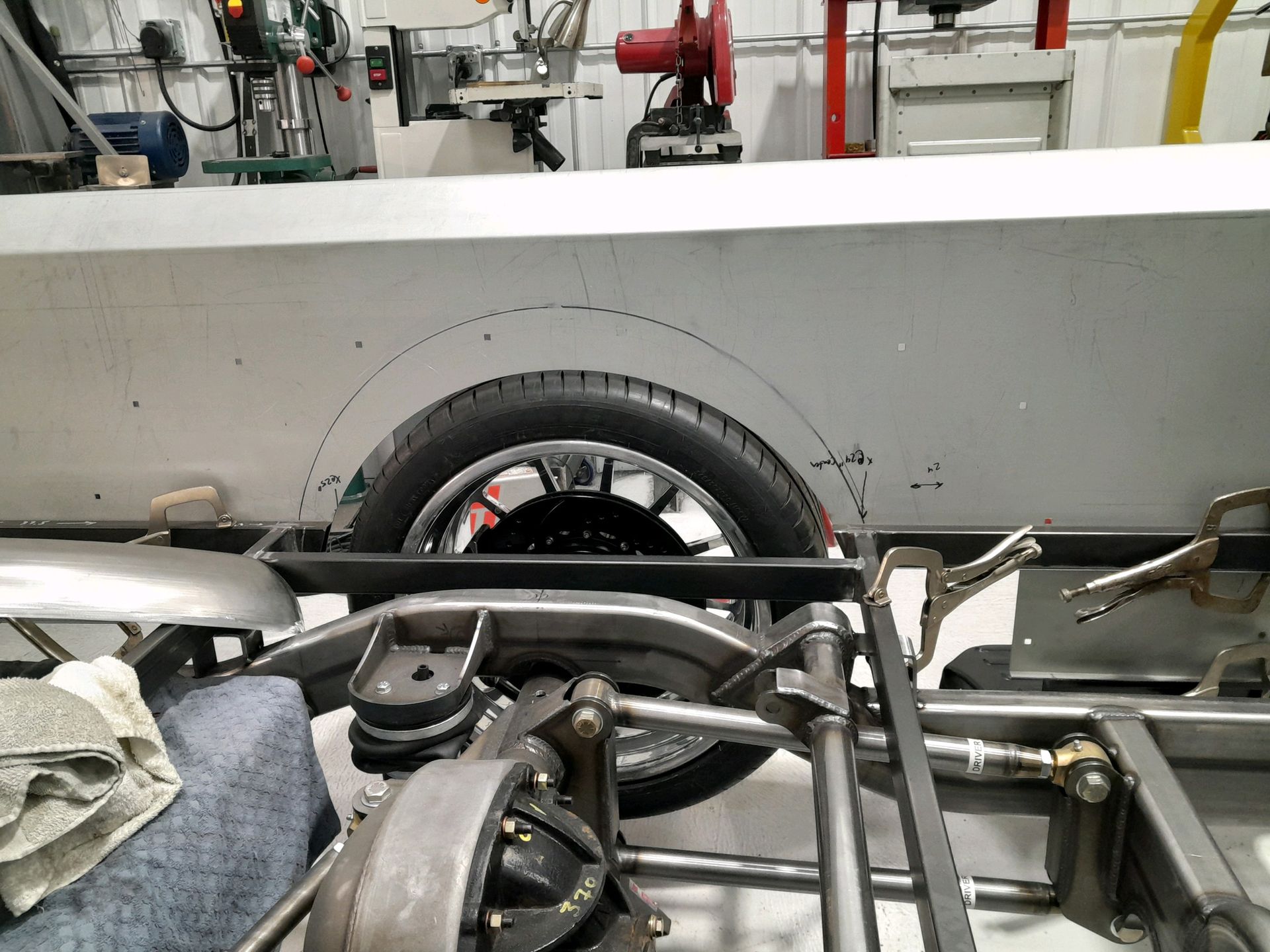 Tire and exposed car chassis parts in an auto repair shop, with tools and equipment in the background.