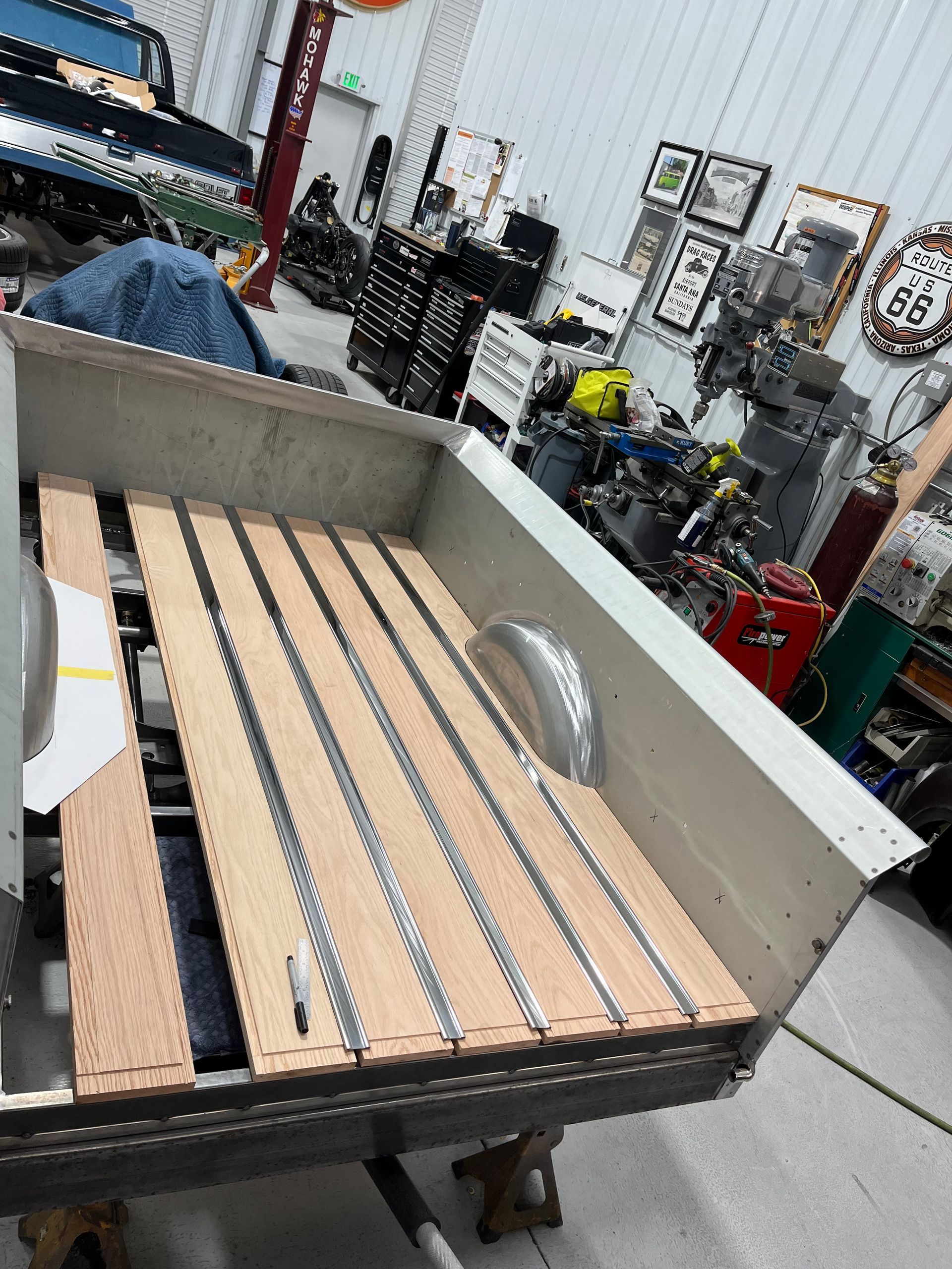 Workbench with a white truck bed panel and wooden slats in an industrial workshop.