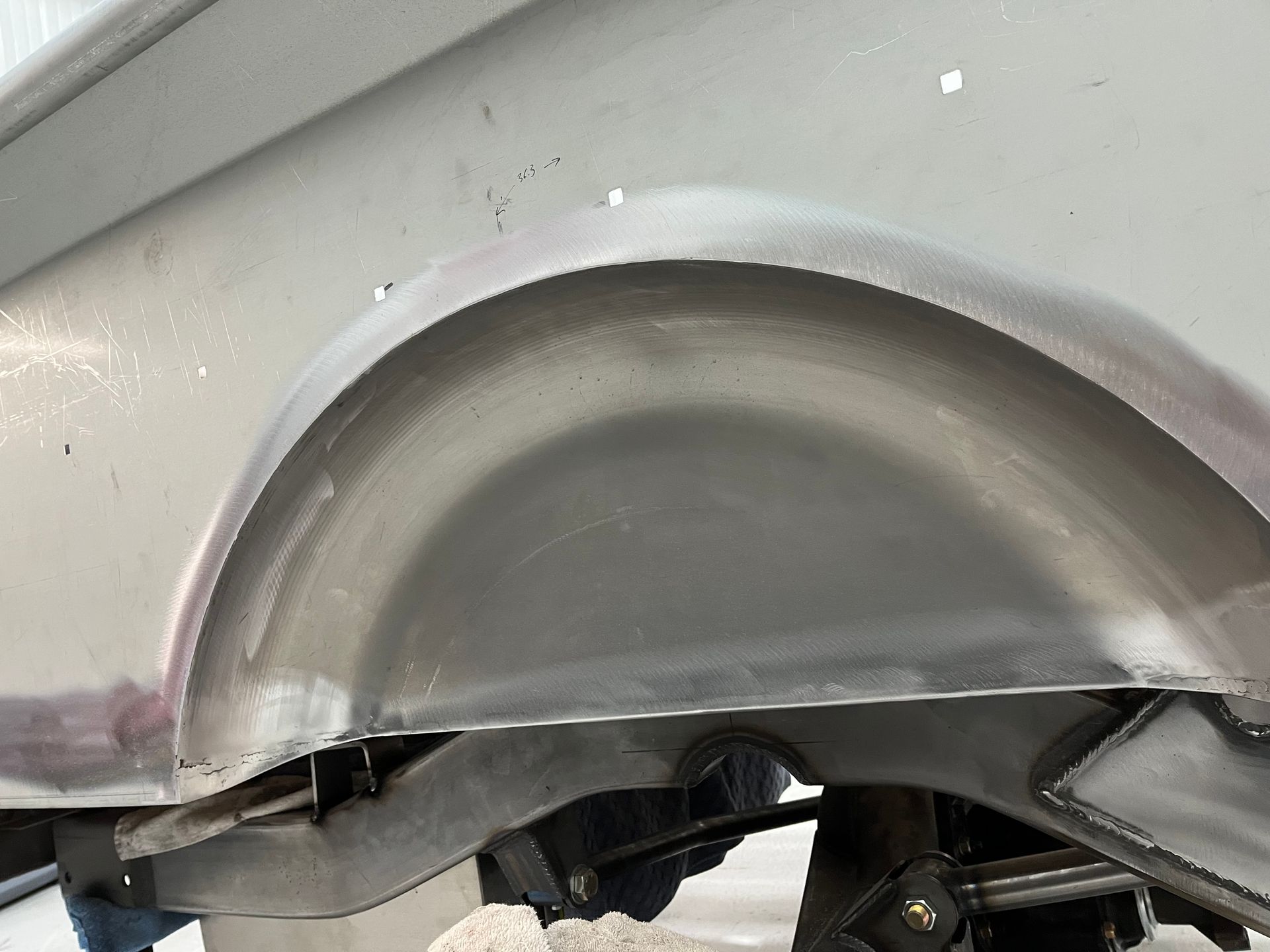 Close-up of a silver car’s damaged wheel arch with a dented fender and exposed inner panel