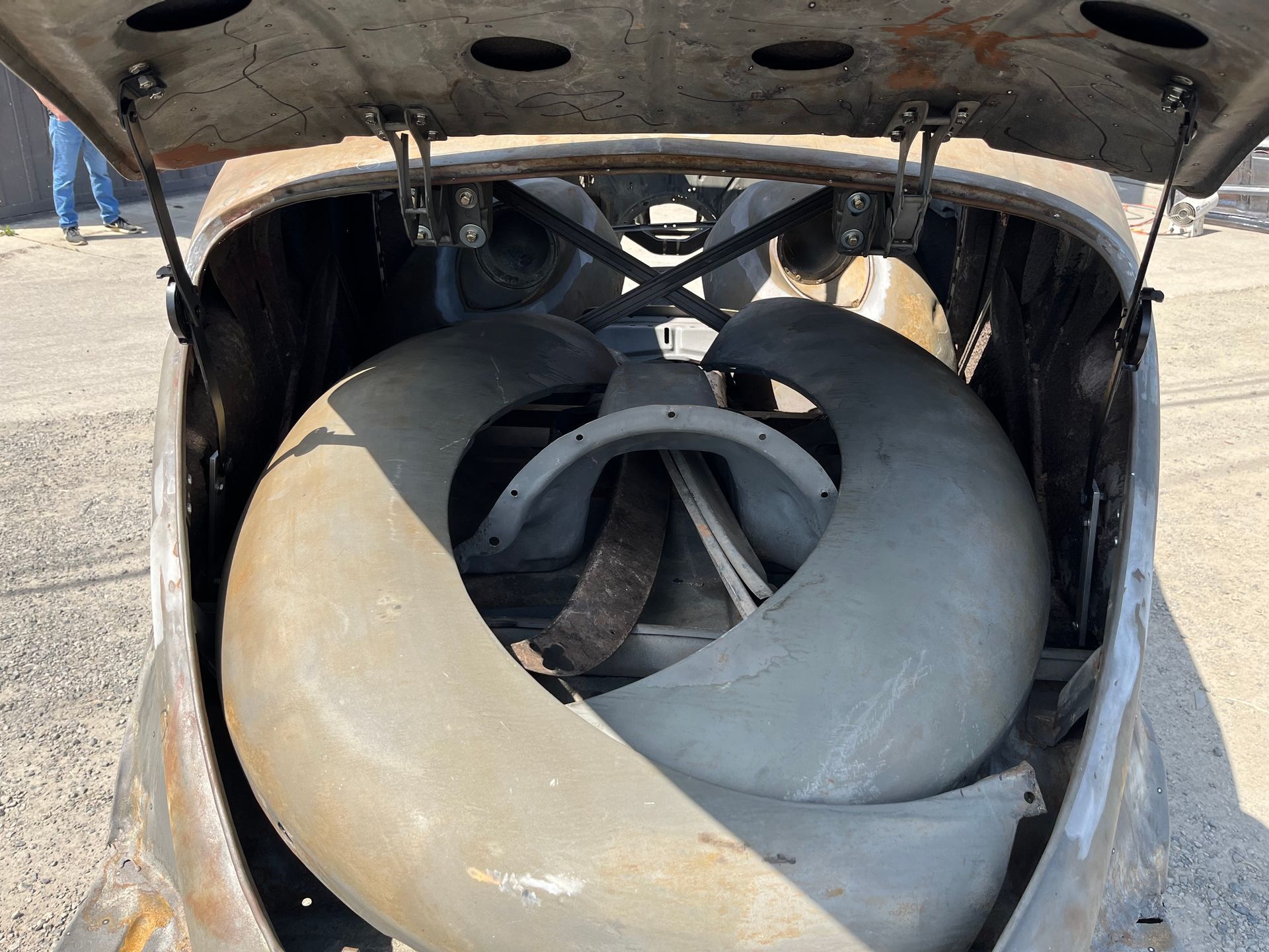 Large gray industrial fan or turbine blades inside an open metal enclosure outdoors.