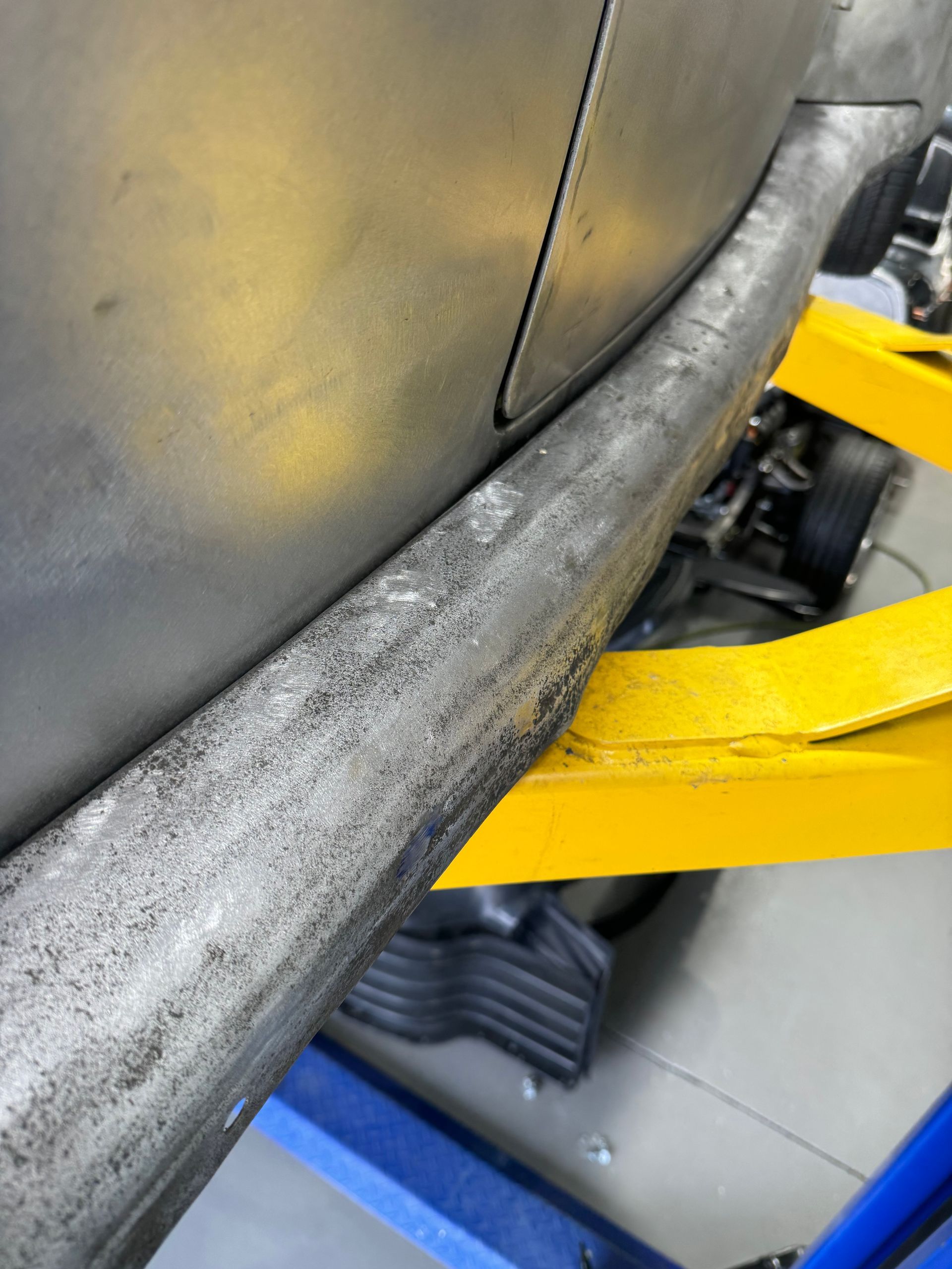 Close-up of a worn car tire on a yellow jack lift in a garage