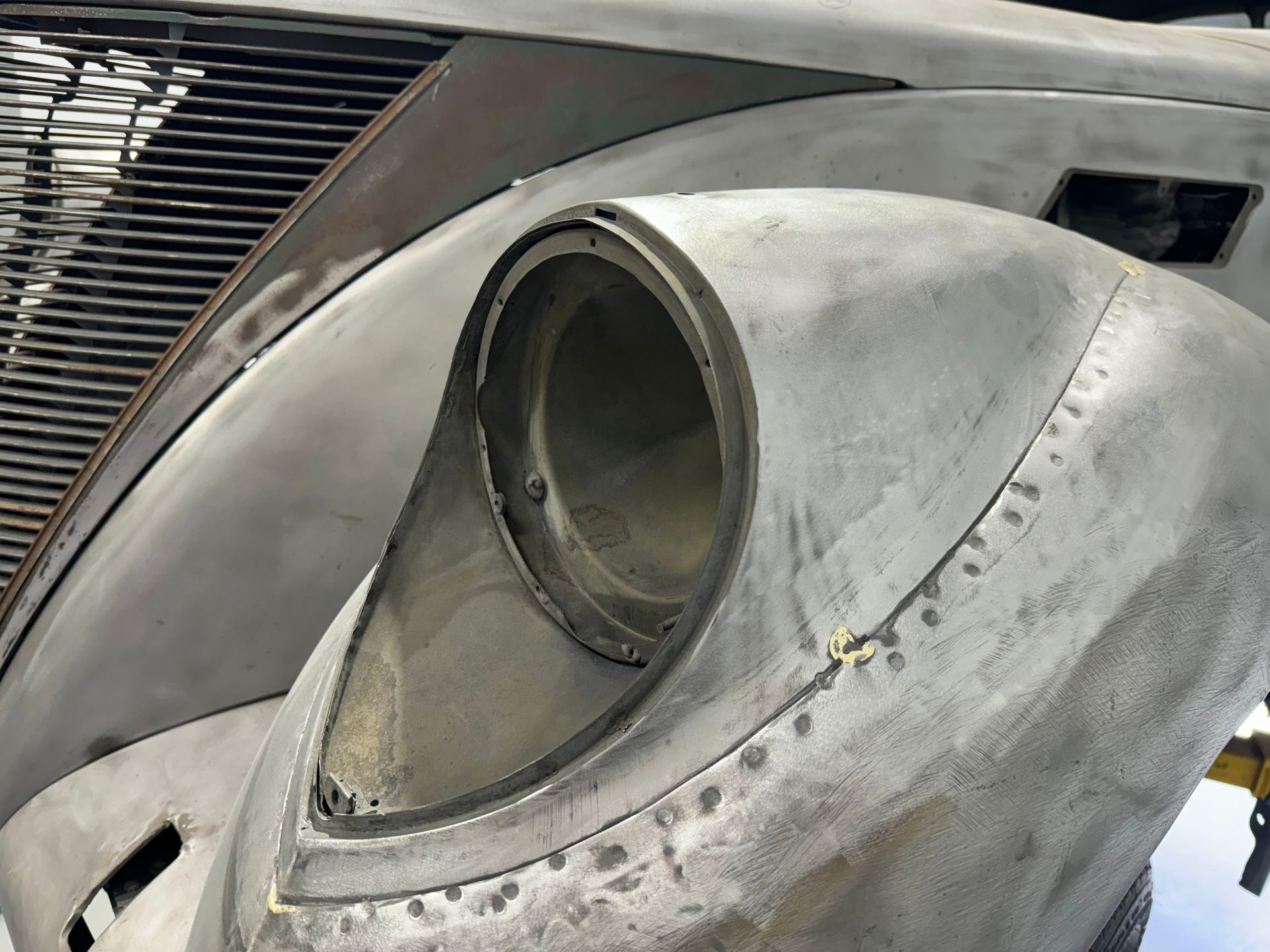 Close-up of a silver aircraft fuselage with a circular engine intake or vent opening