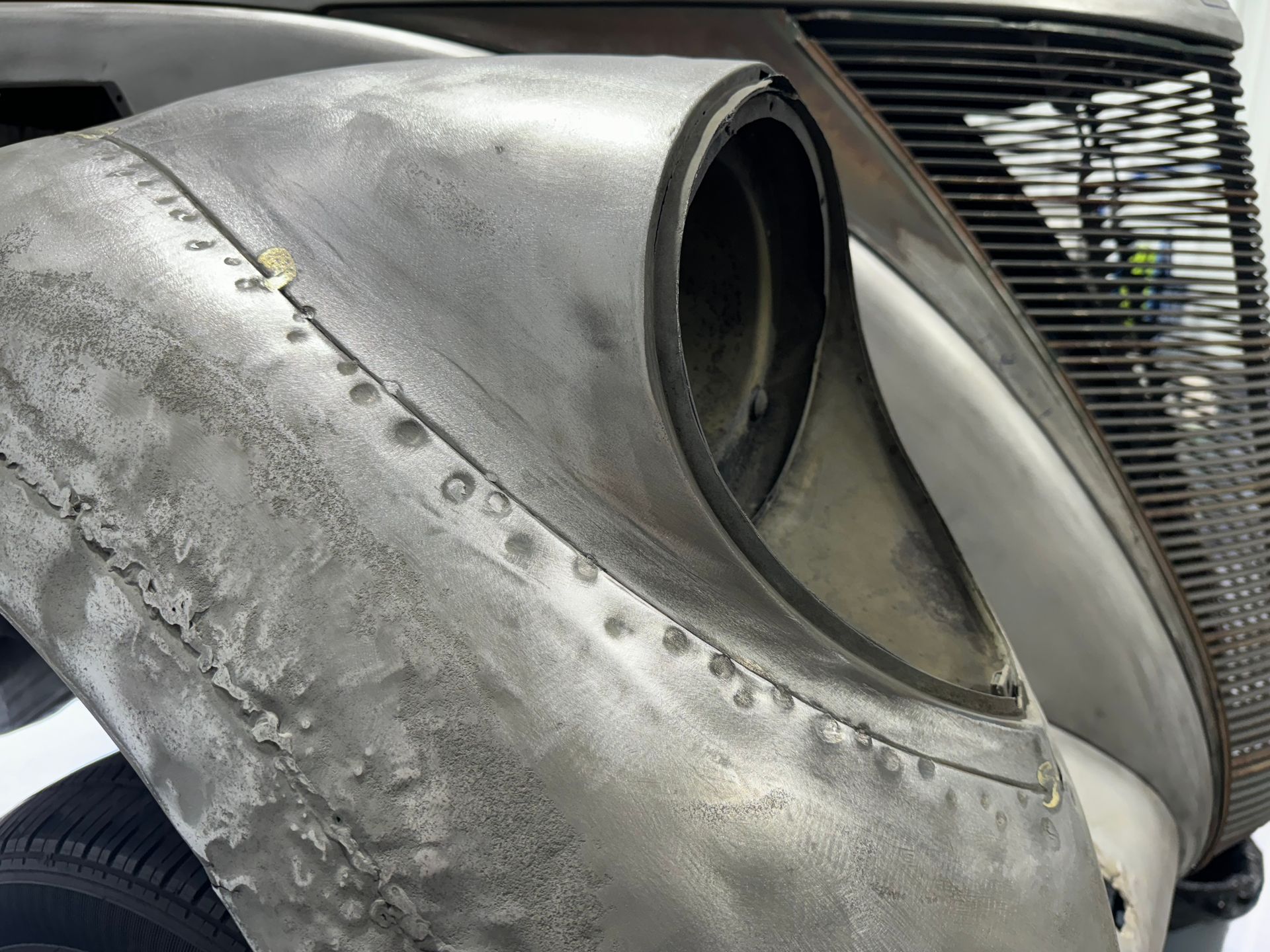 Close-up of a weathered metal aircraft nose or fuselage with a circular opening and riveted panels