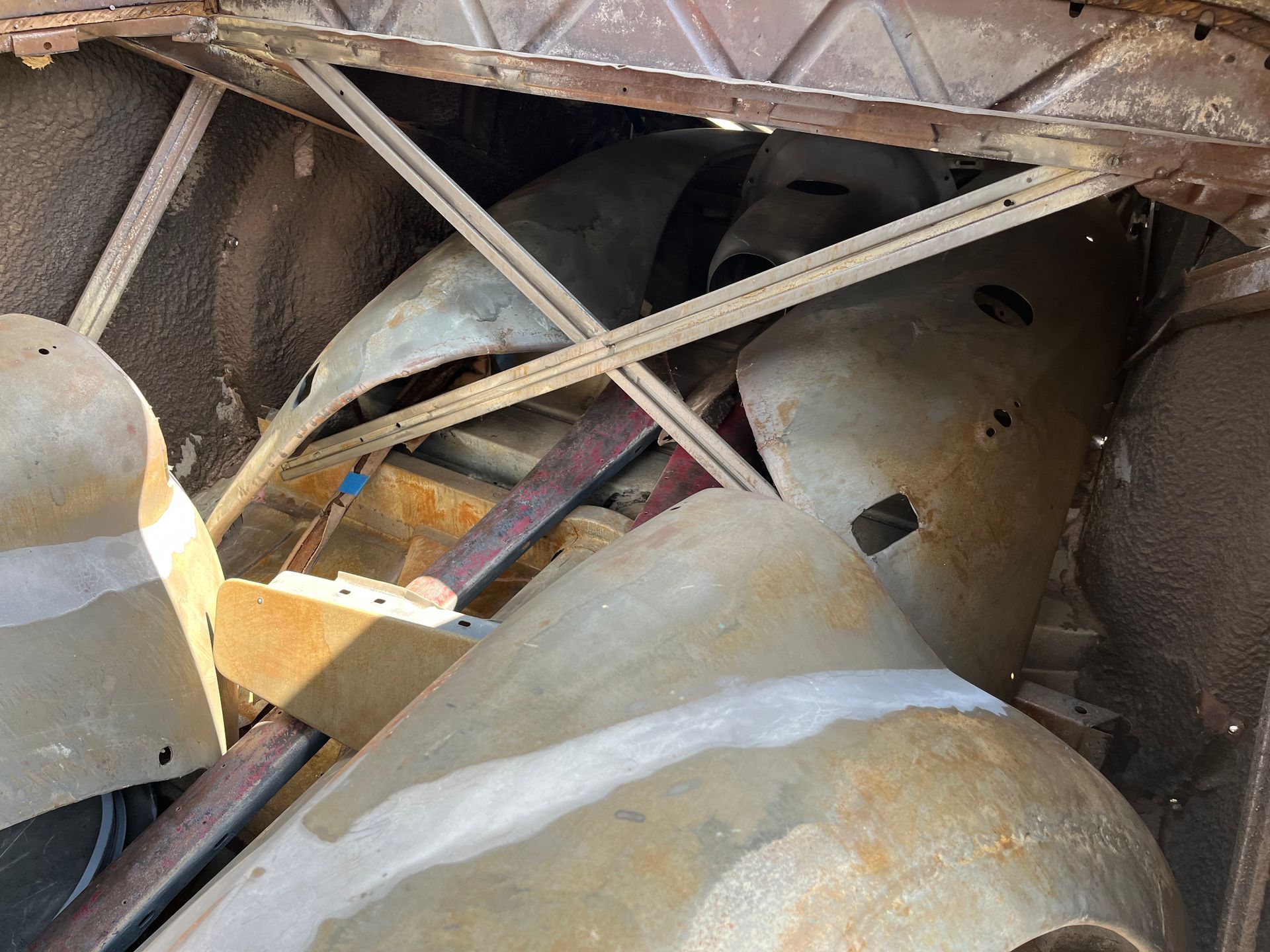 Close-up of rusted industrial pipes and metal beams inside a cramped structure
