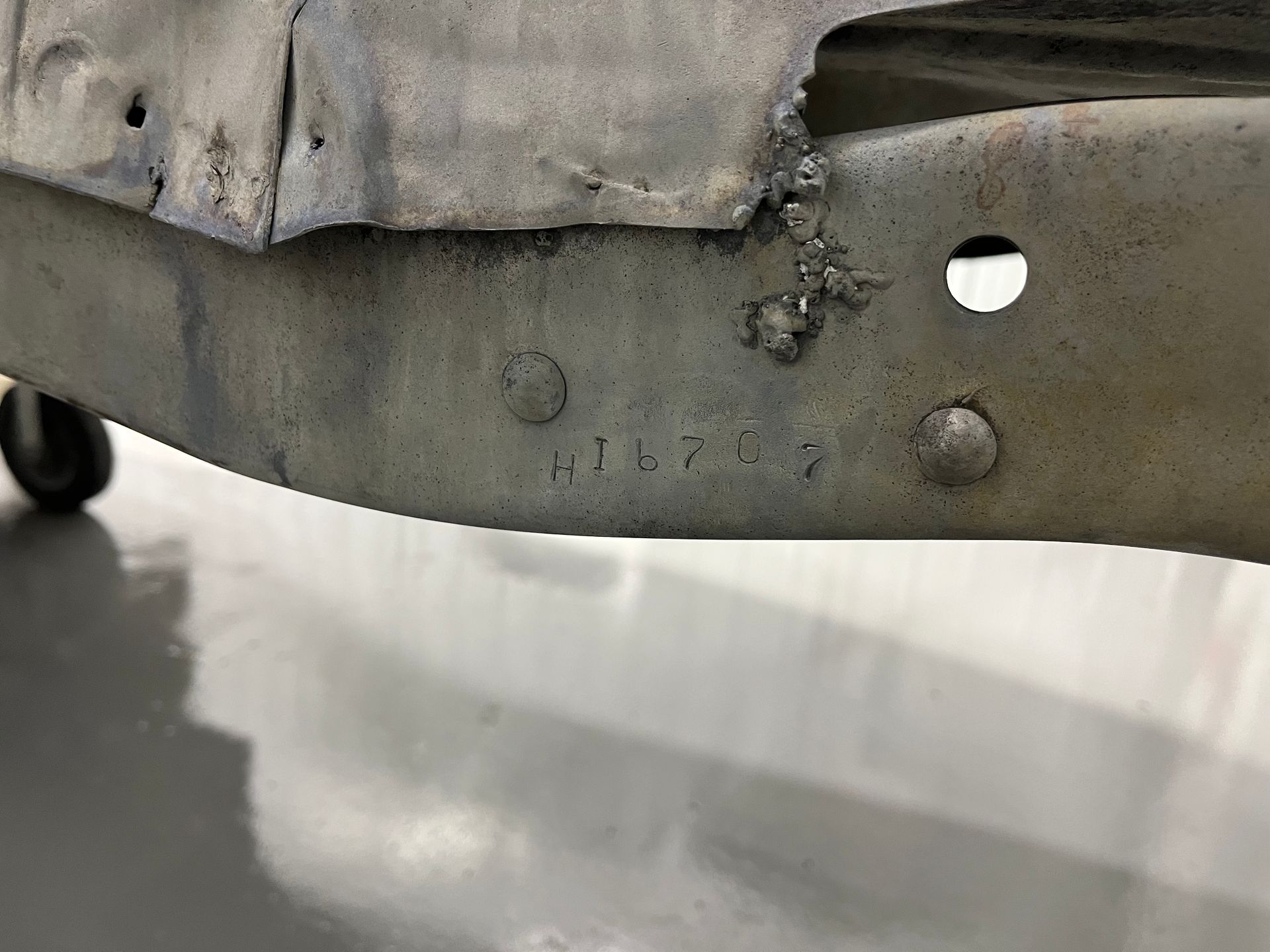 Close-up of a gray, worn fabric and metal cart frame with a wheel visible underneath.