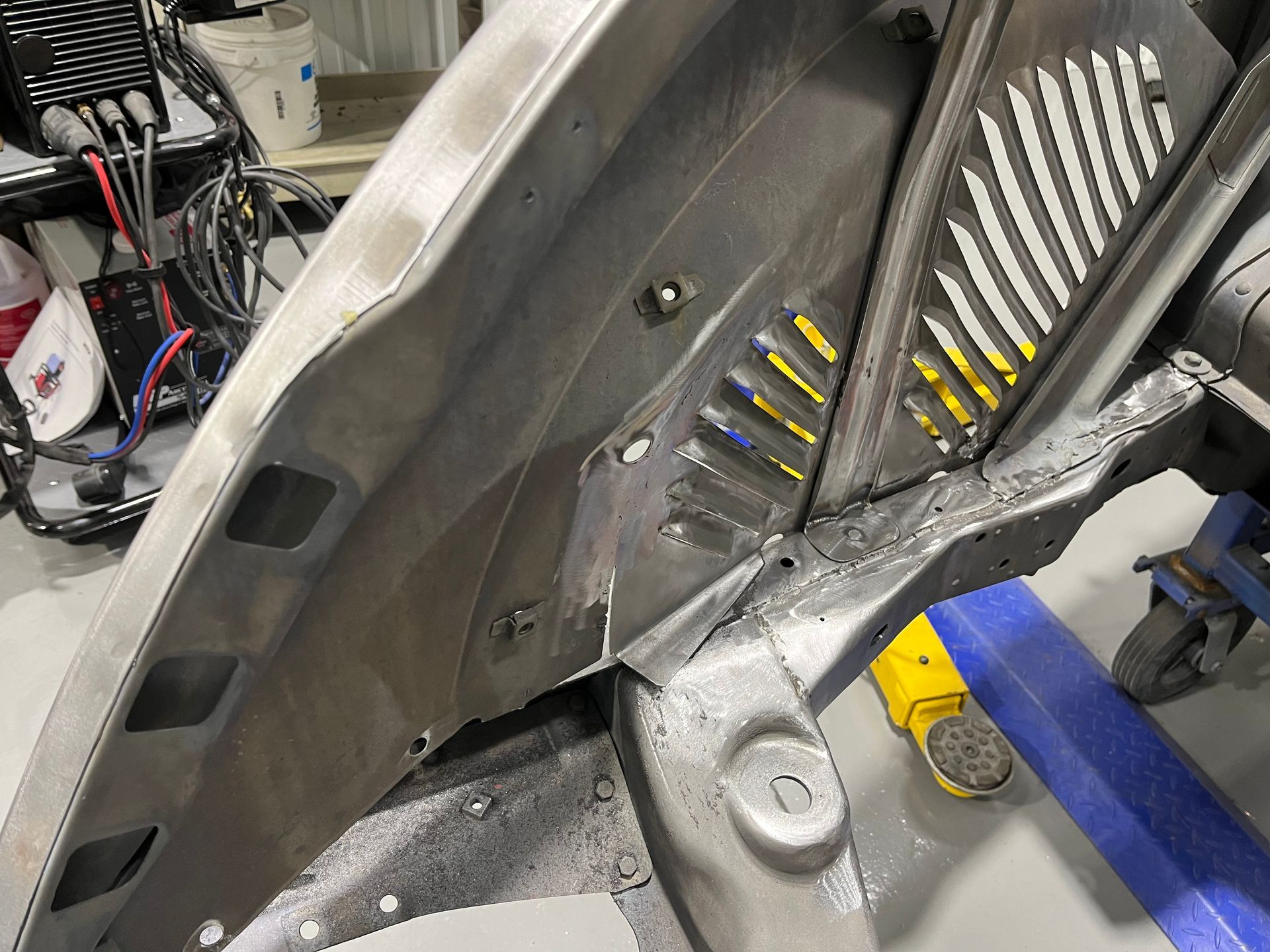 Close-up of a gray vehicle interior panel with vents, wiring, and a blue tape roll on a workbench