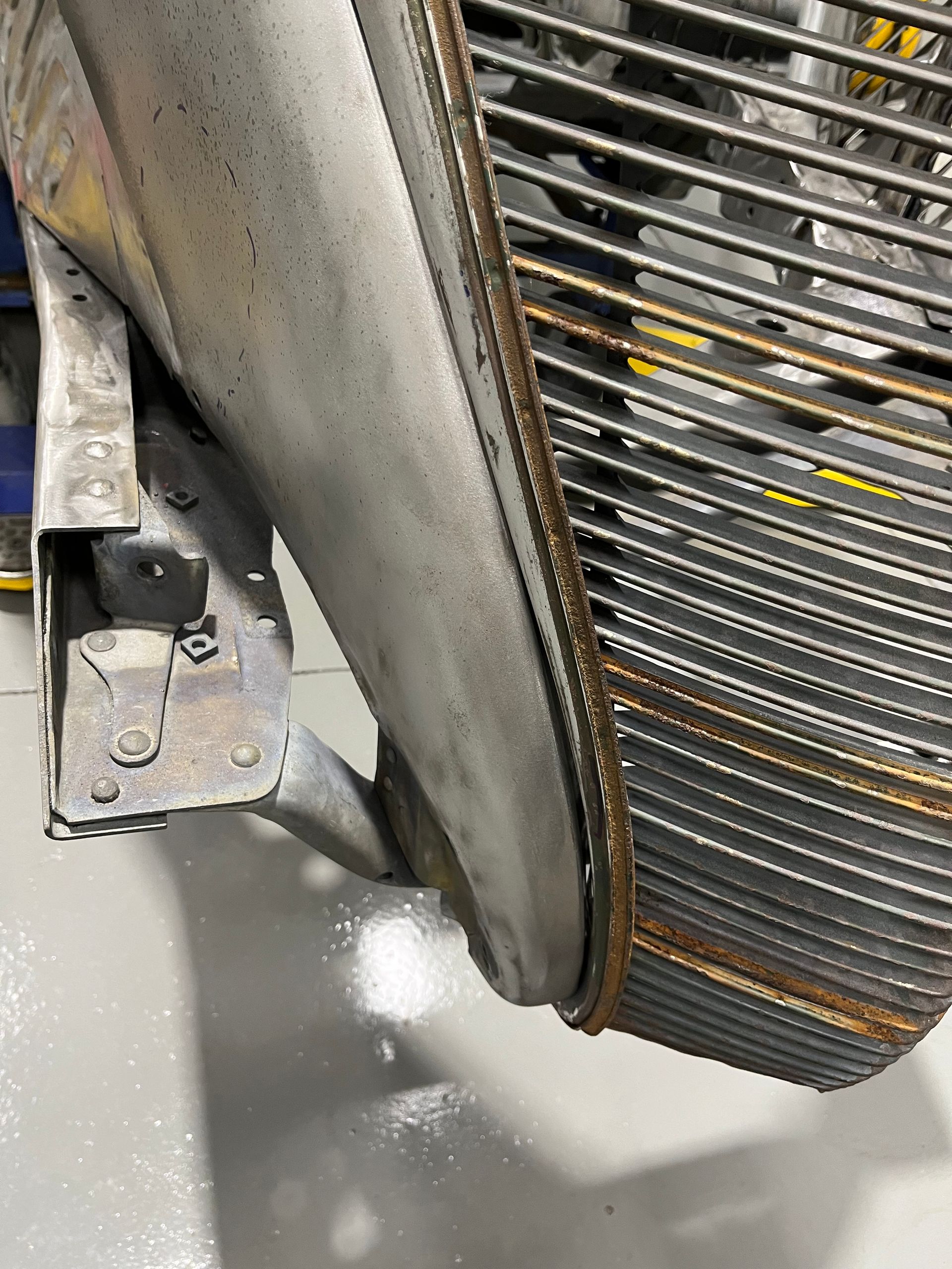 Close-up of a dusty industrial fan blade and metal grill with a rusted edge.