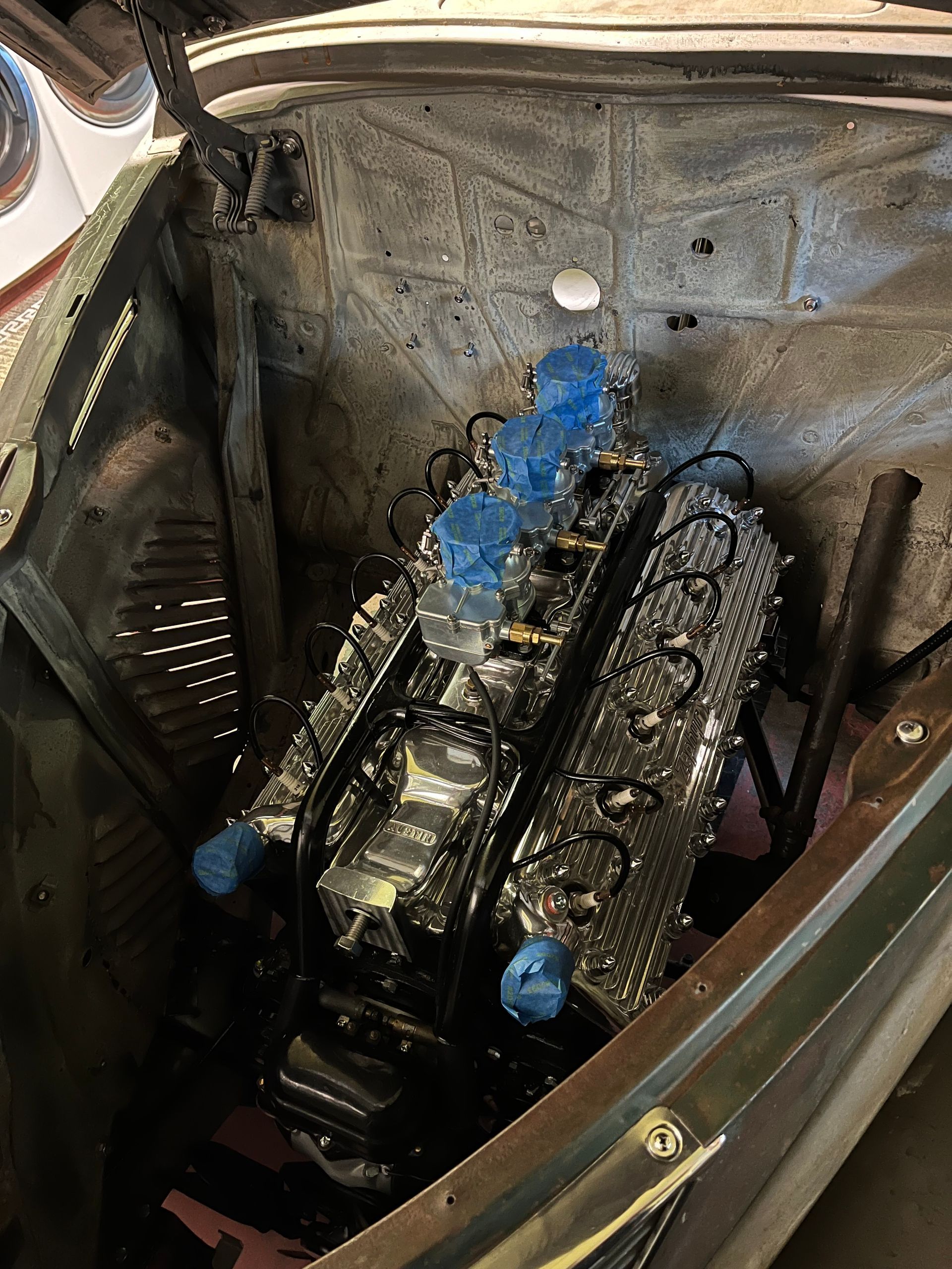 Engine bay with a partially disassembled car engine and blue tape inside a vehicle compartment