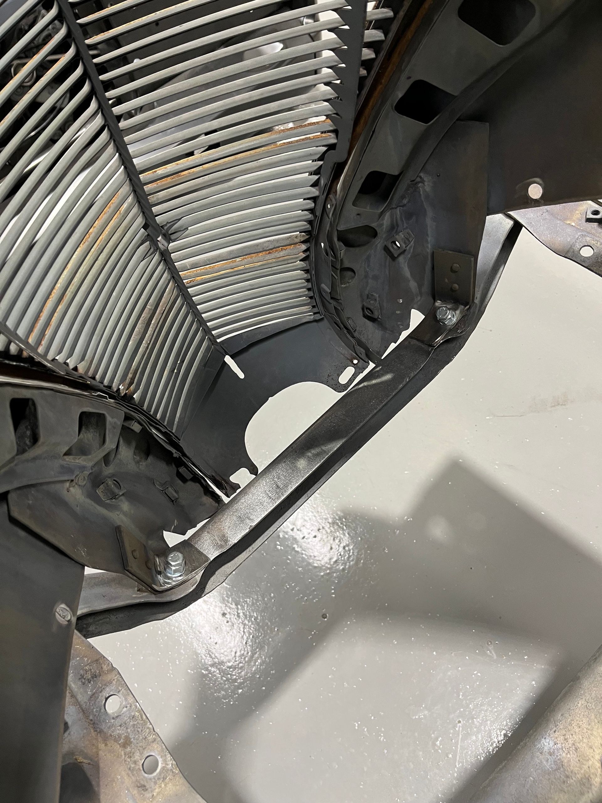 Close-up of a dirty black fan or grille over a light gray surface with debris below
