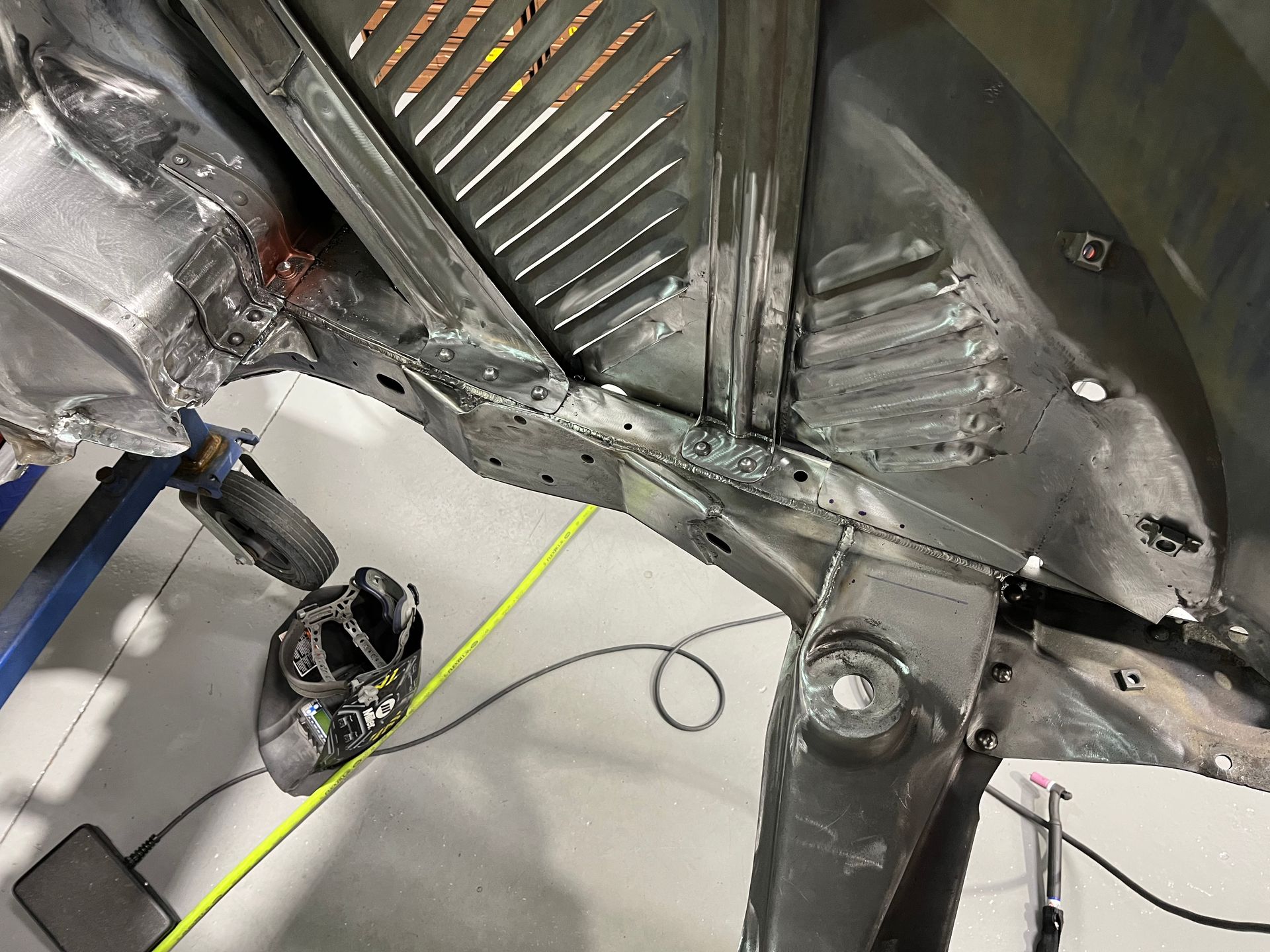 Metal car interior floor and underbody panels with wiring and tools visible during repair