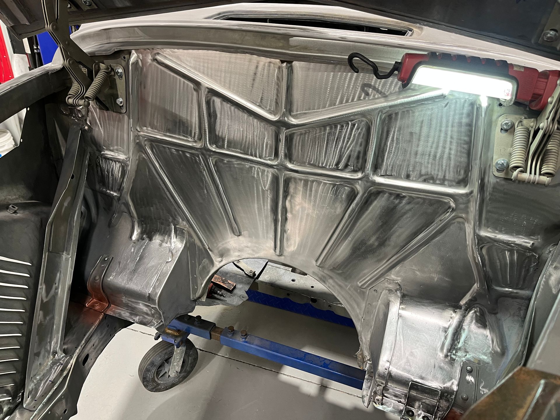 Metal-lined interior of a vehicle body with reflective insulation and a blue support frame on caster wheels