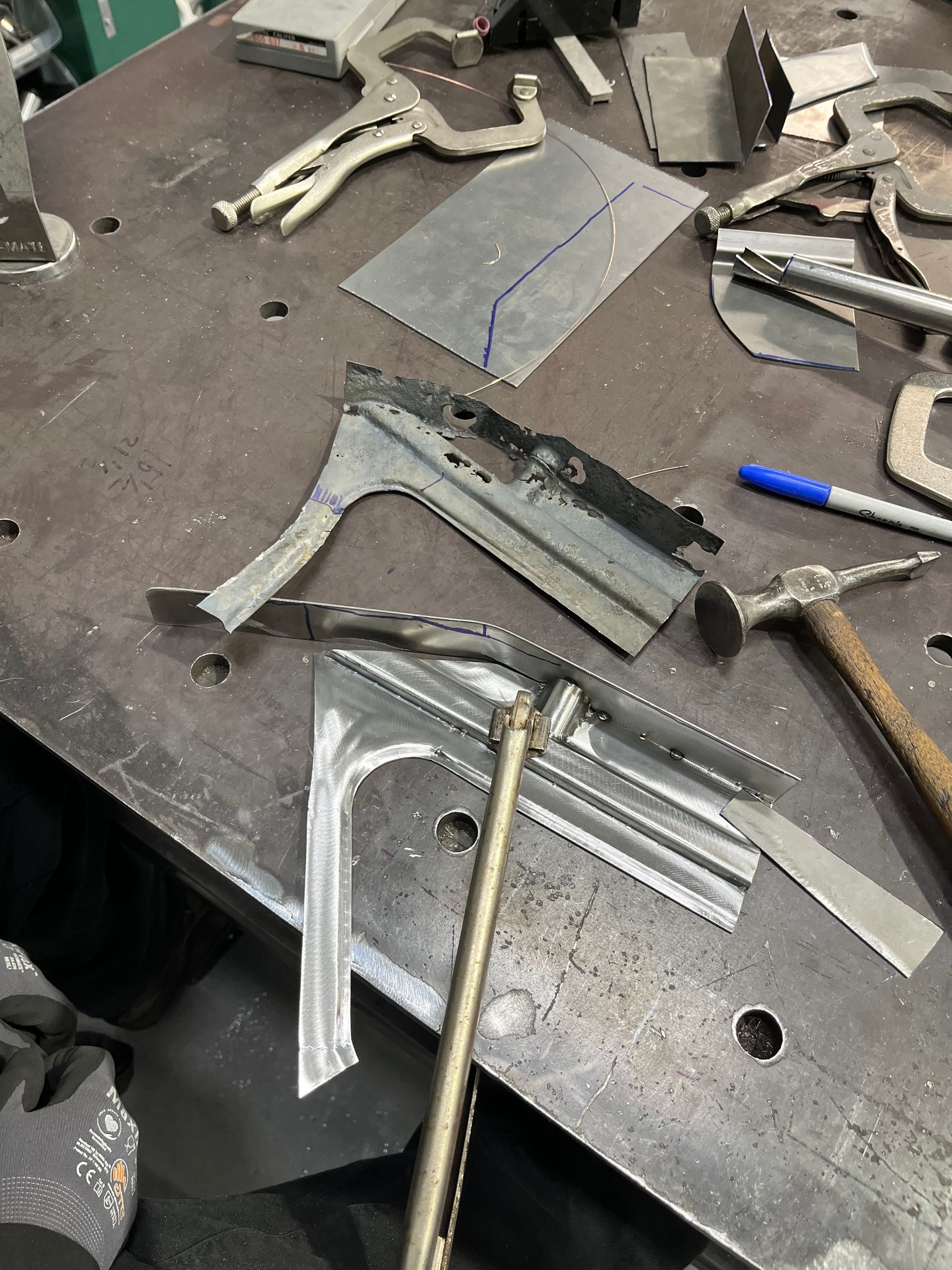 Metal hand tools and scrap pieces scattered on a workbench in a workshop.