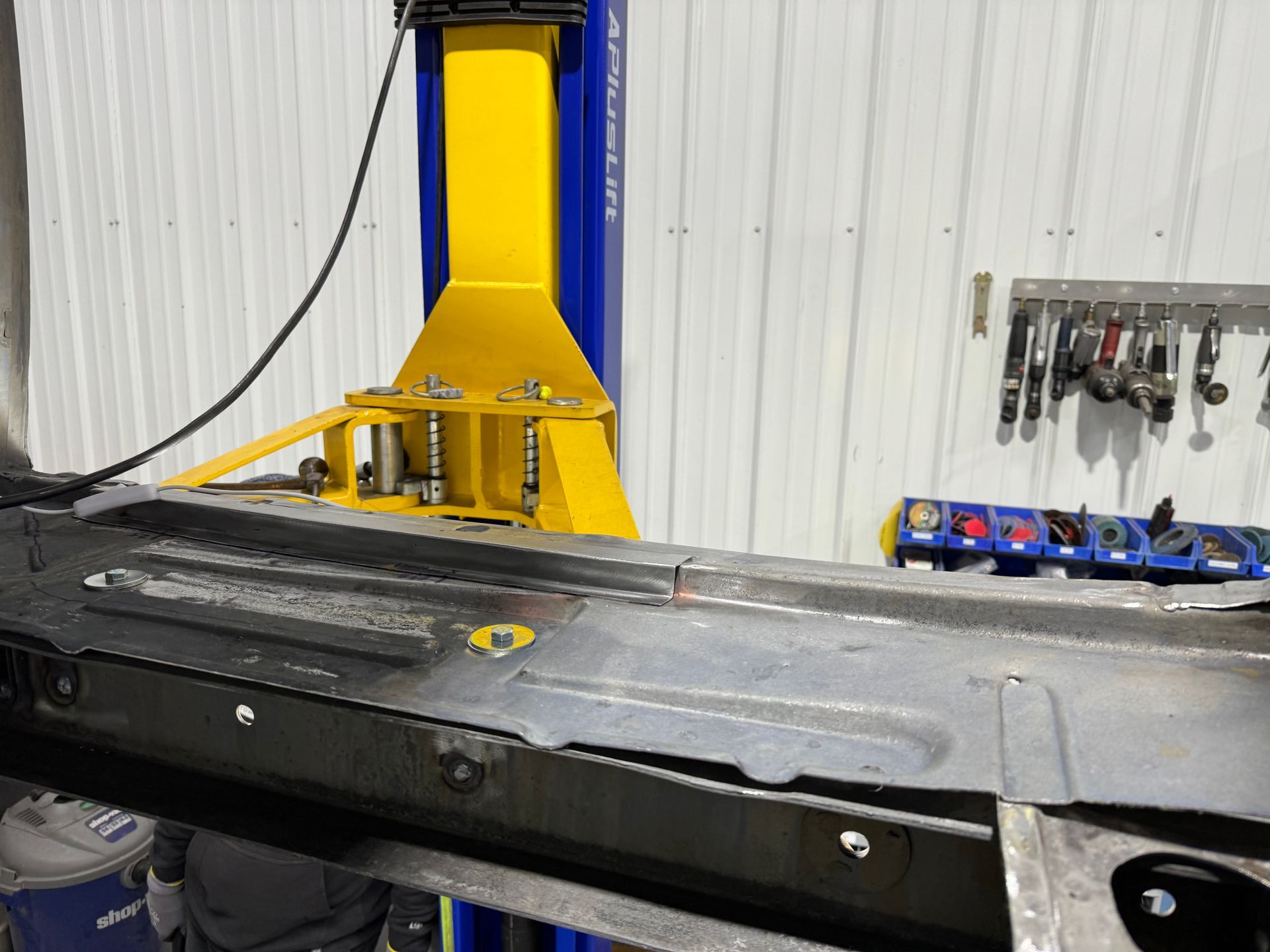 Industrial machine with blue and yellow vertical column beside a black work surface in a workshop