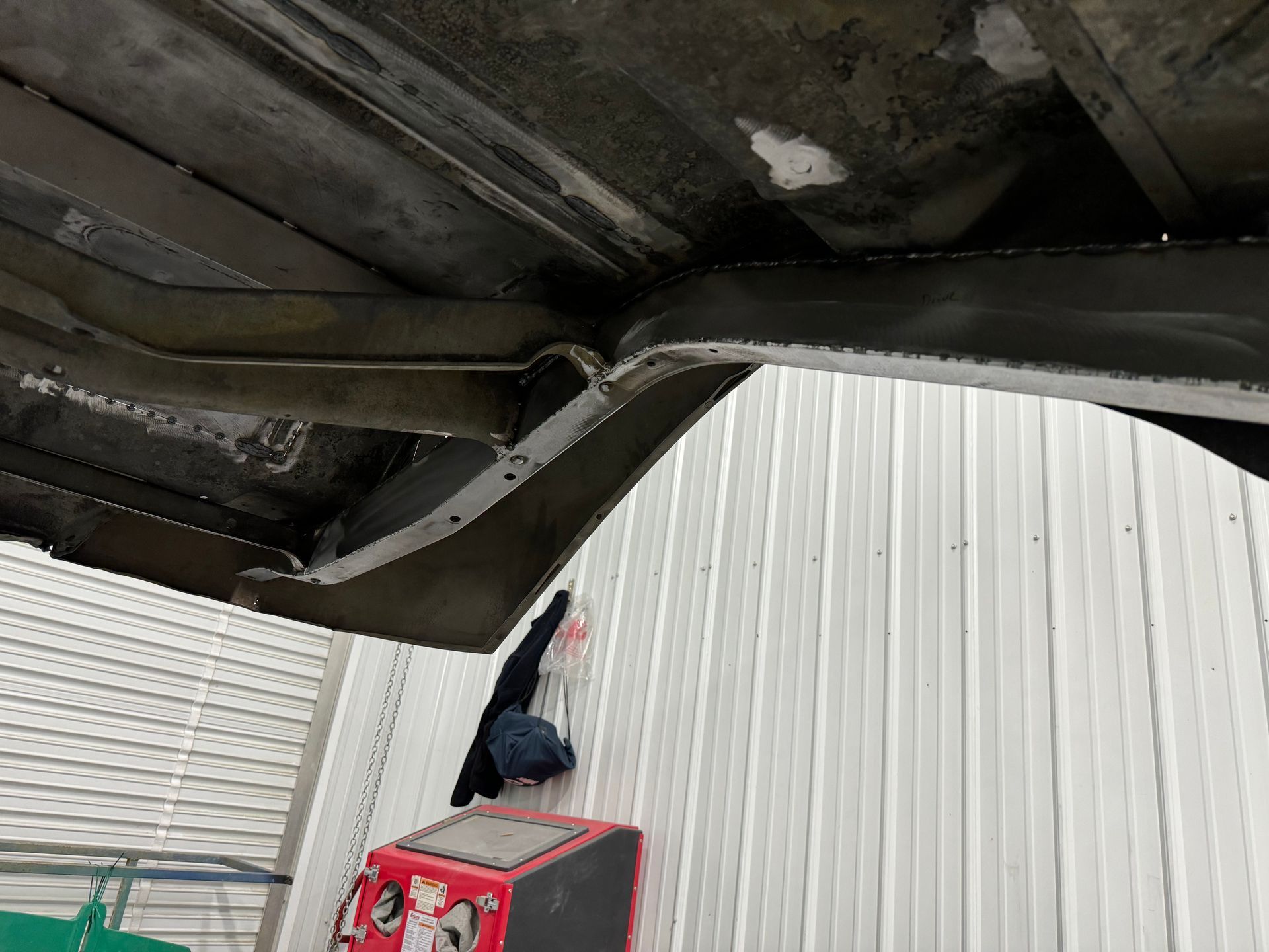 Person on a red crate reaching up to a dark metal ceiling in an industrial space