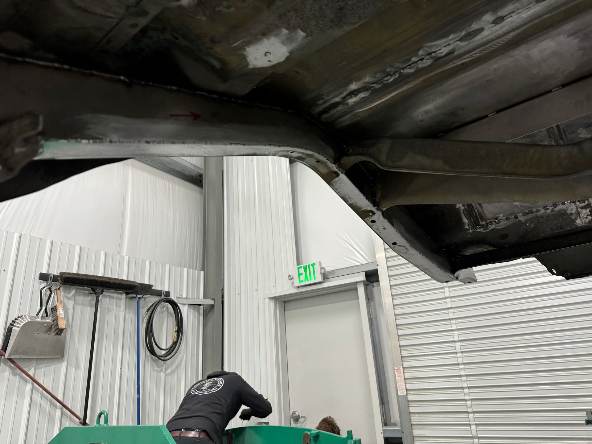 Worker bent near a white door under a damaged black ceiling in an industrial room