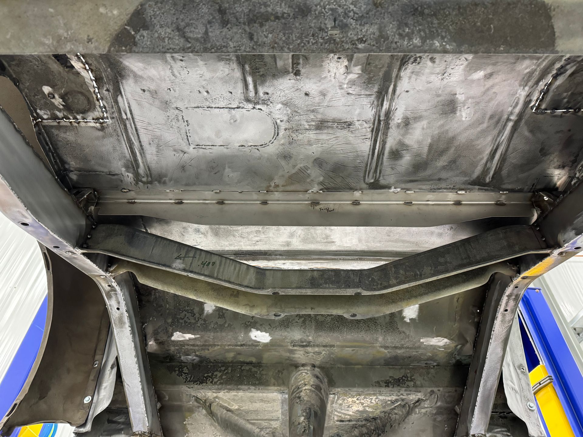 Close-up of a damaged metal undercarriage with a bent support beam and scuffed gray panels.