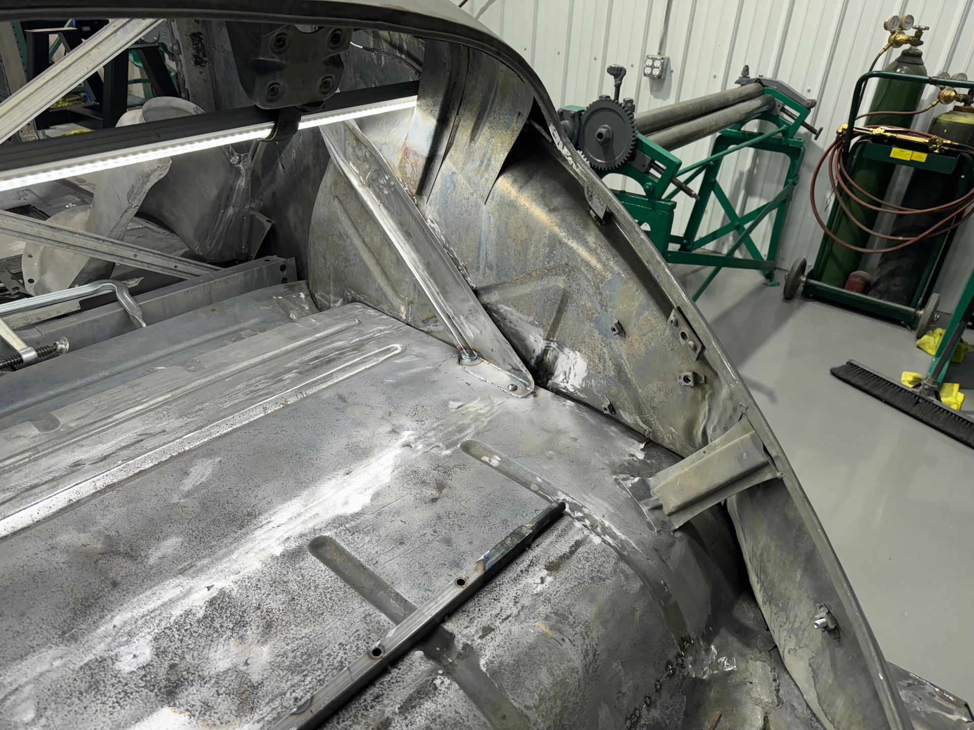 Damaged metallic industrial machine or vehicle frame in a workshop, with bent panels and exposed structure