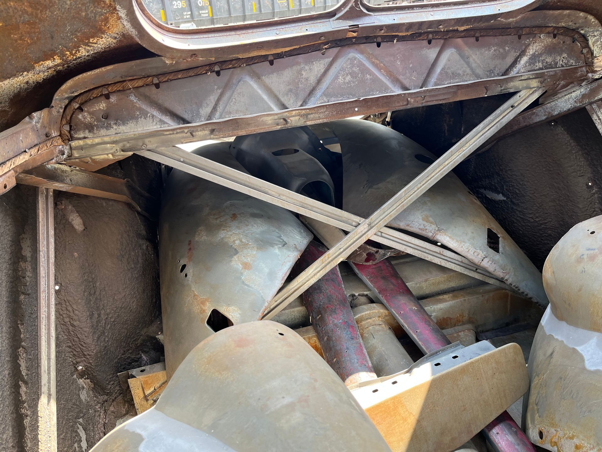 Close-up of a rusty mechanical compartment with metal braces and cylindrical parts inside.