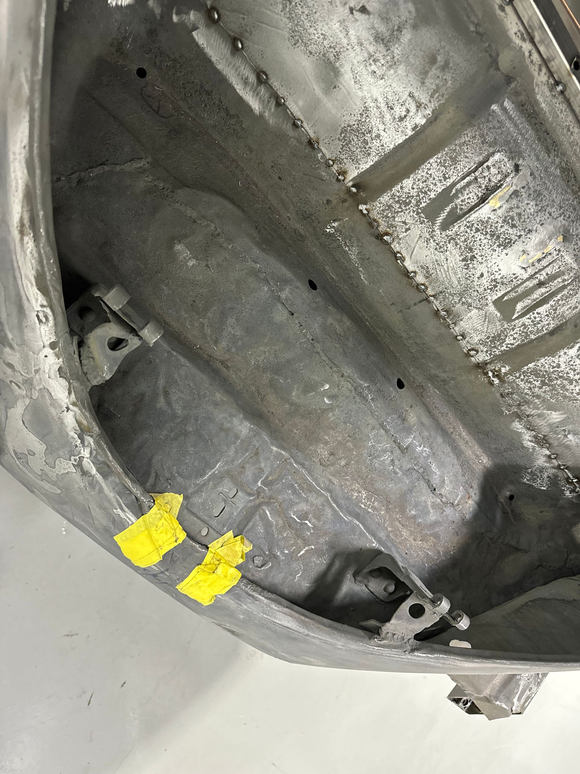 Close-up of a dirty gray metal interior with two yellow paint marks and mounting bolts.
