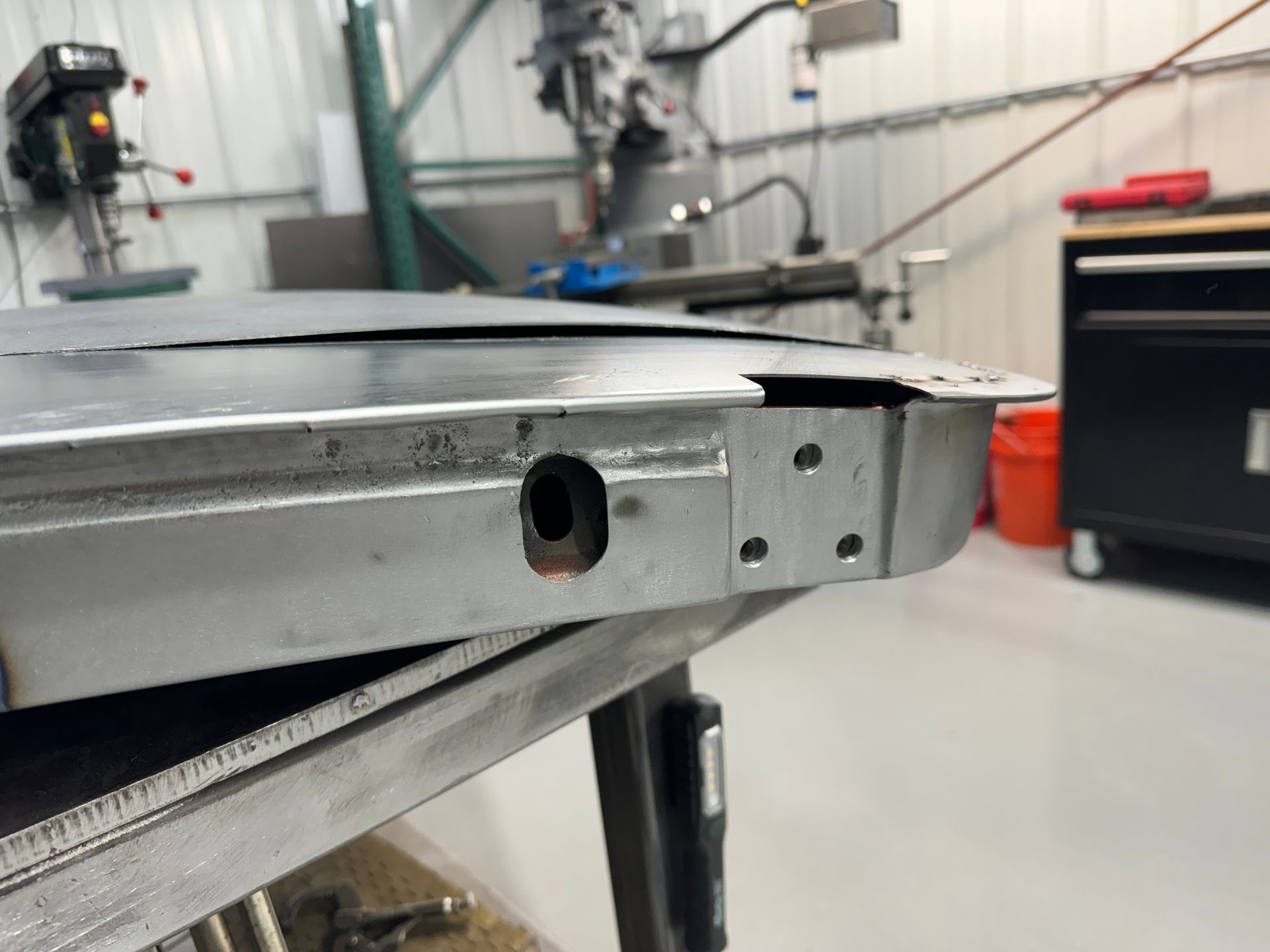 Metal workbench edge with a bolt hole and bracket in a workshop