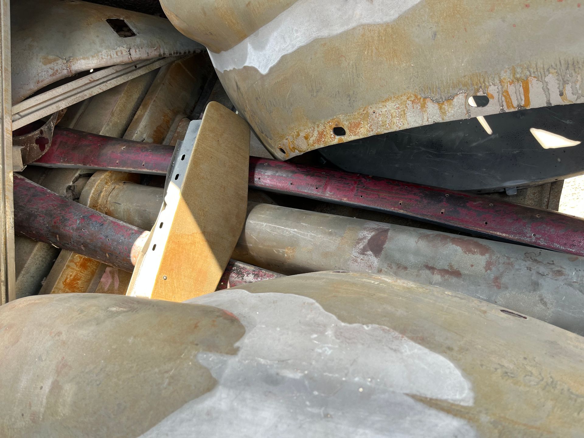 Close-up of tangled industrial pipes and metal beams with rust and dust.