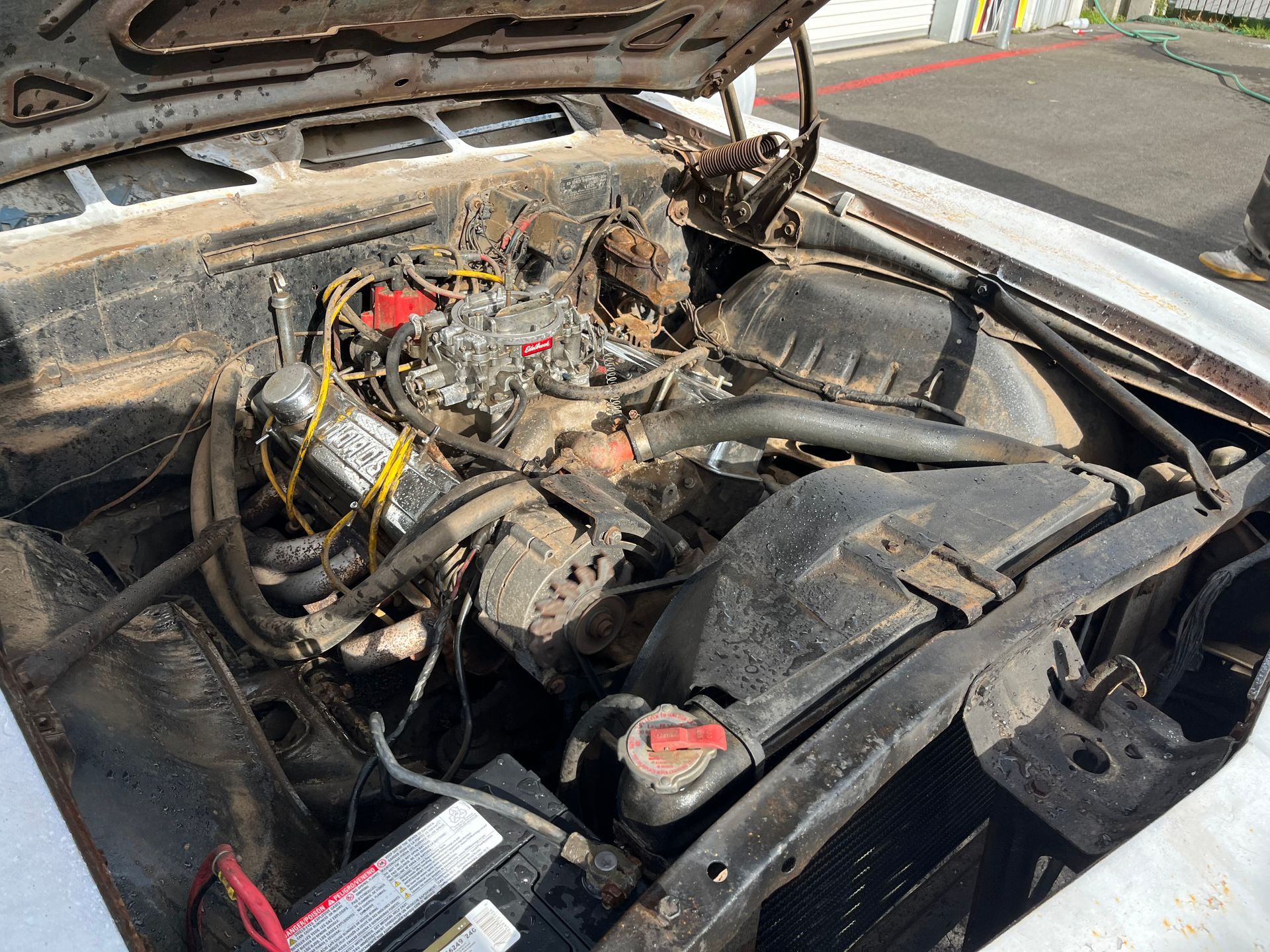 Burned car engine bay with hood open, showing heavy fire damage and charred components