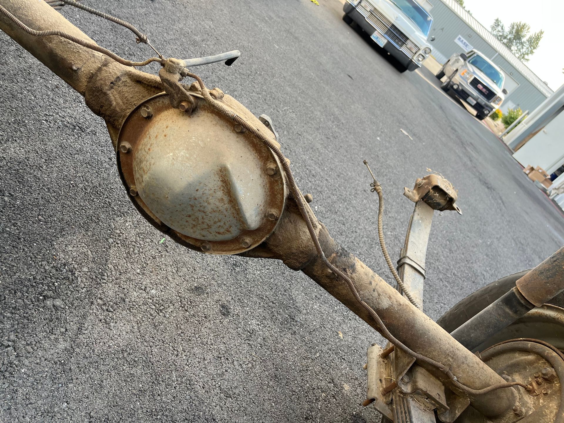 Close-up of a rusty truck axle and differential undercarriage on an asphalt lot