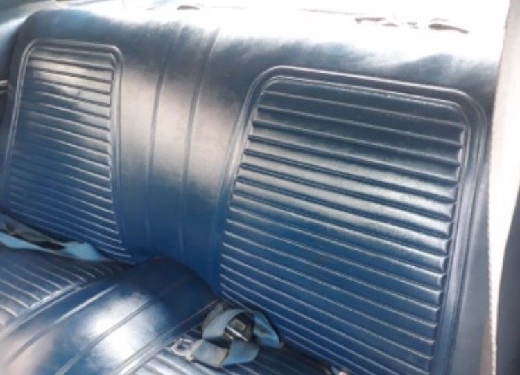 Blue vinyl car seats with ribbed backrests and a center armrest in a vehicle interior
