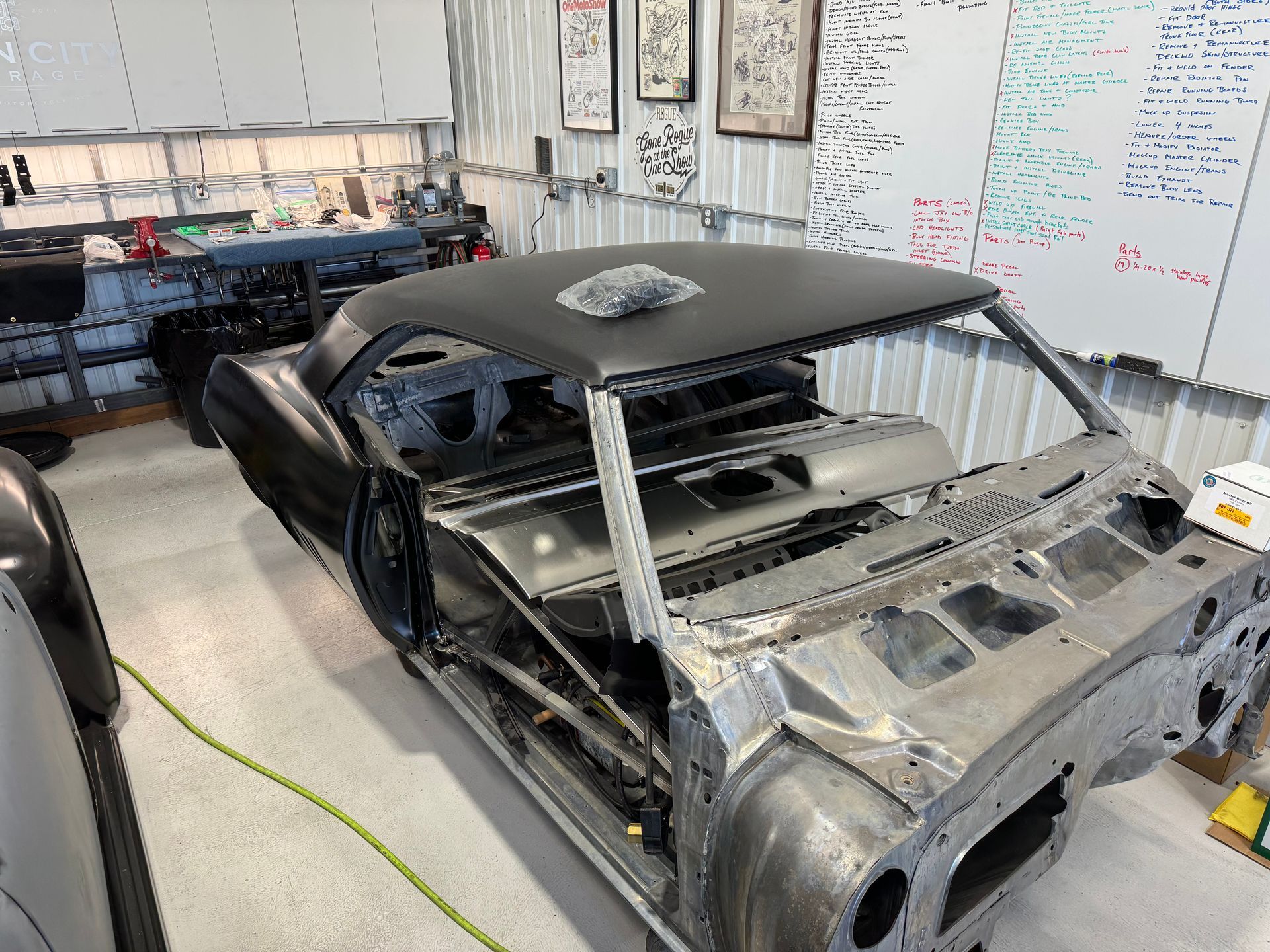 Partially stripped black sports car in a workshop, with exposed frame and removed front body panels