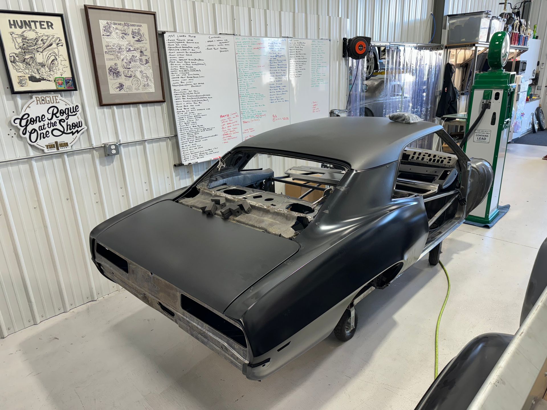 Partially restored black classic car in a workshop, with parts removed and tools nearby