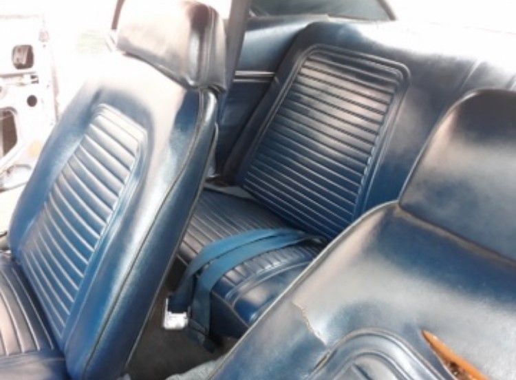 Blue leather car seats in a vehicle interior, with front and rear bench seats visible.