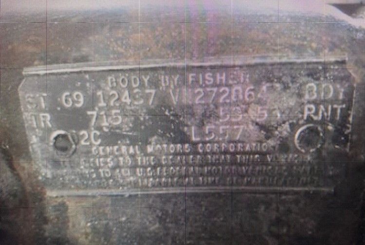 Close-up of a dusty metal motor ID plate with stamped numbers and faded text.