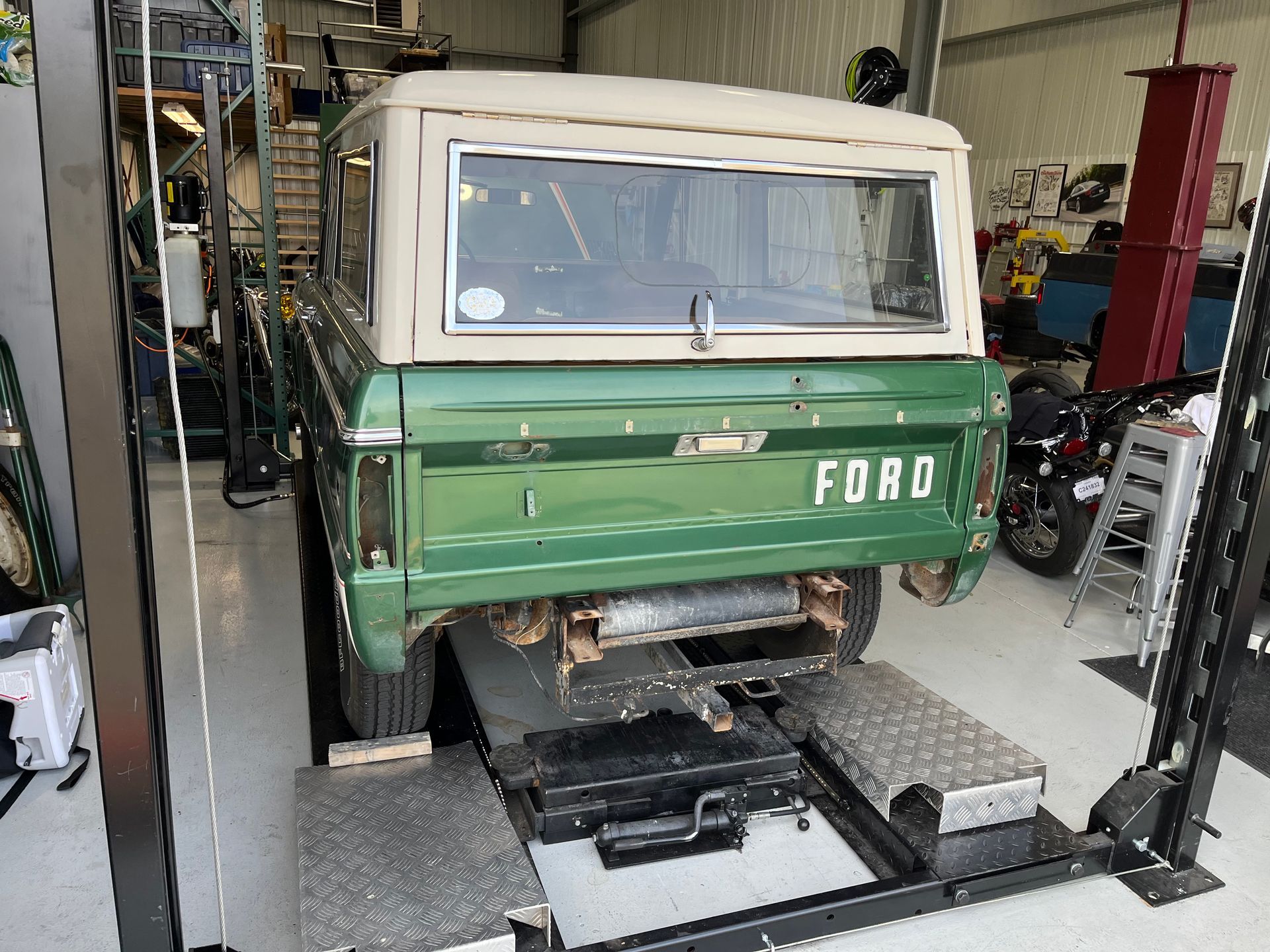 Green and white Ford truck inside a garage on a vehicle lift, front view