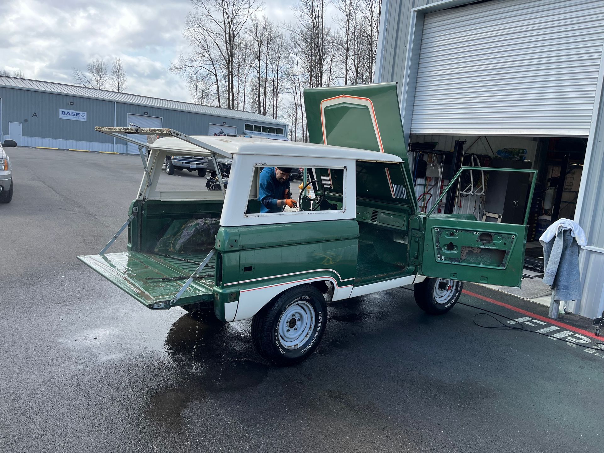 Green utility cart with open doors parked outside a building on a wet lot