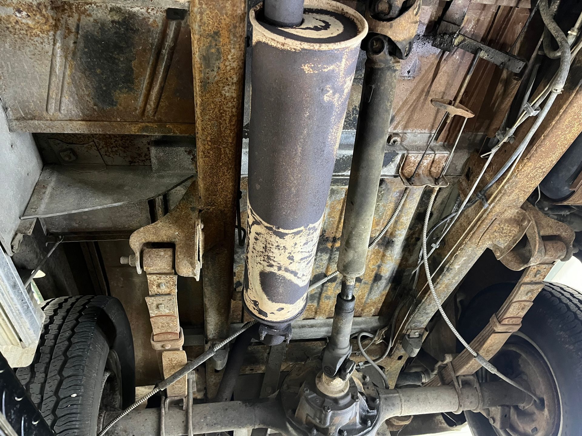 Underside of a vehicle showing the exhaust muffler, suspension, and rear wheels.