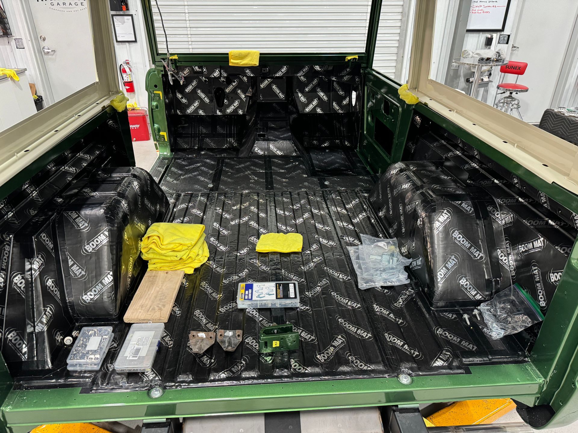 Open truck bed lined with black protective coating and scattered tools, boxes, and taped packages