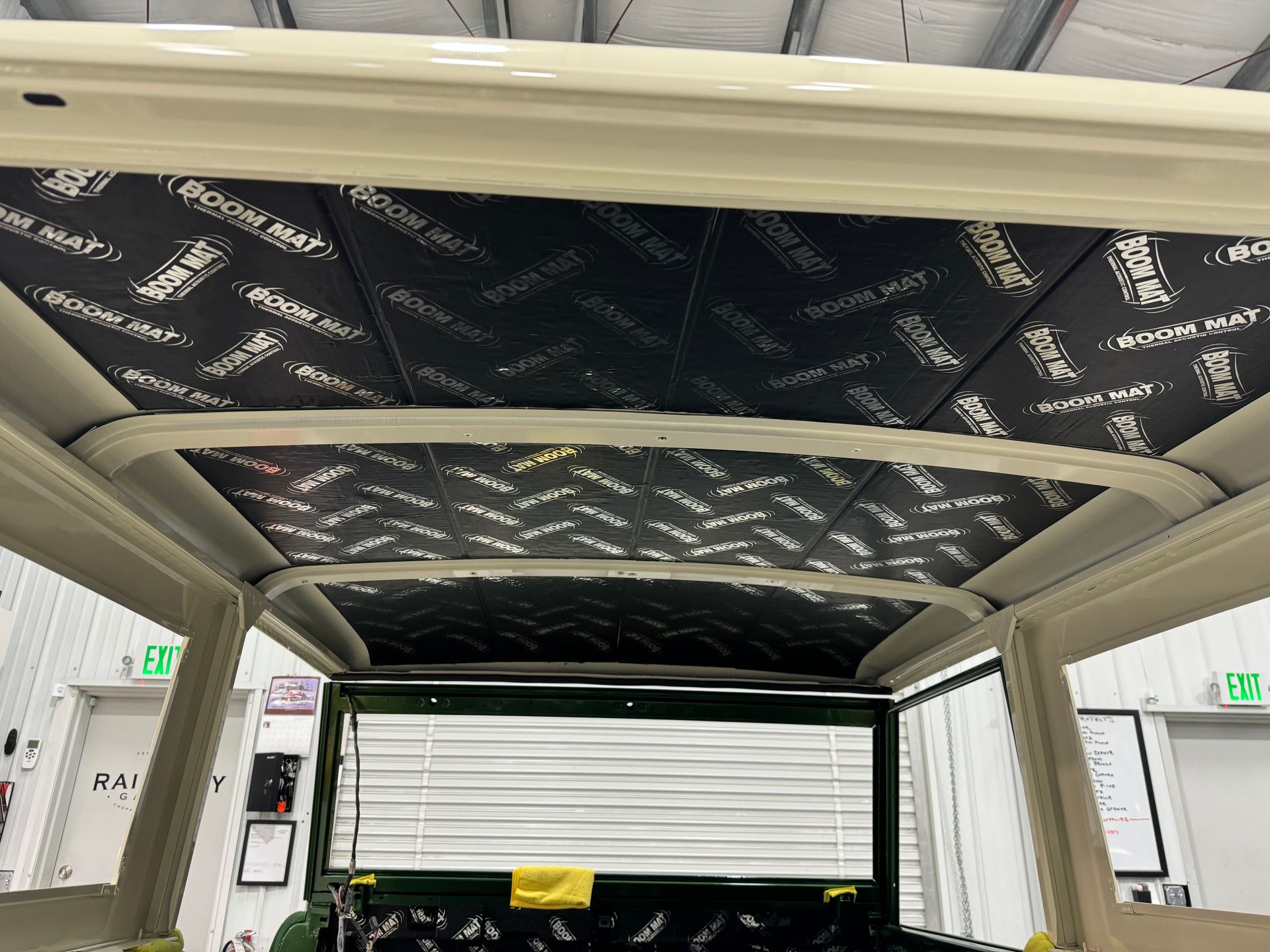 Carport roof frame with black insulation under construction inside a white garage or workshop