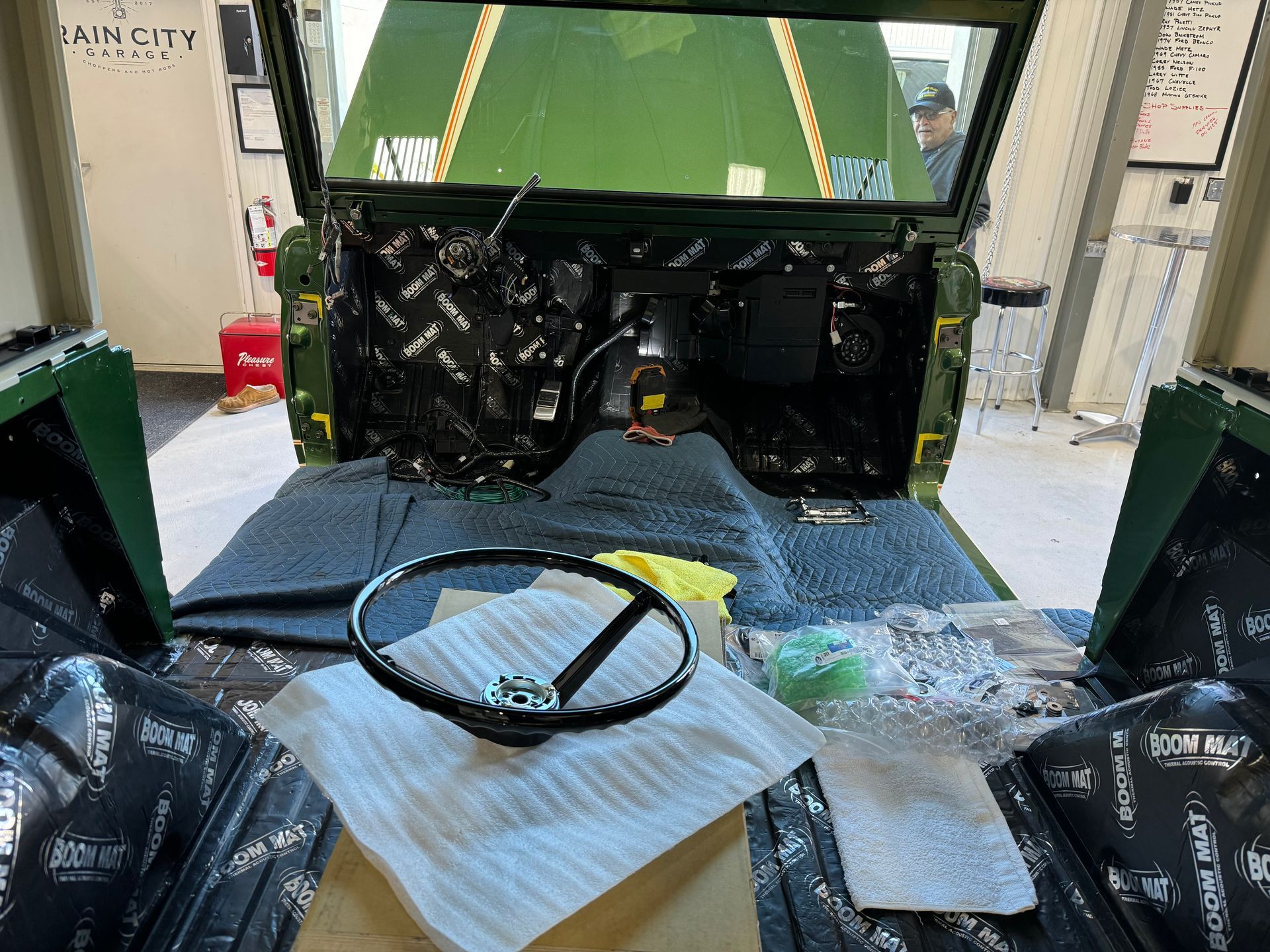 Car interior stripped for repair, with exposed black panels, tools, and parts laid out on a protective blanket.