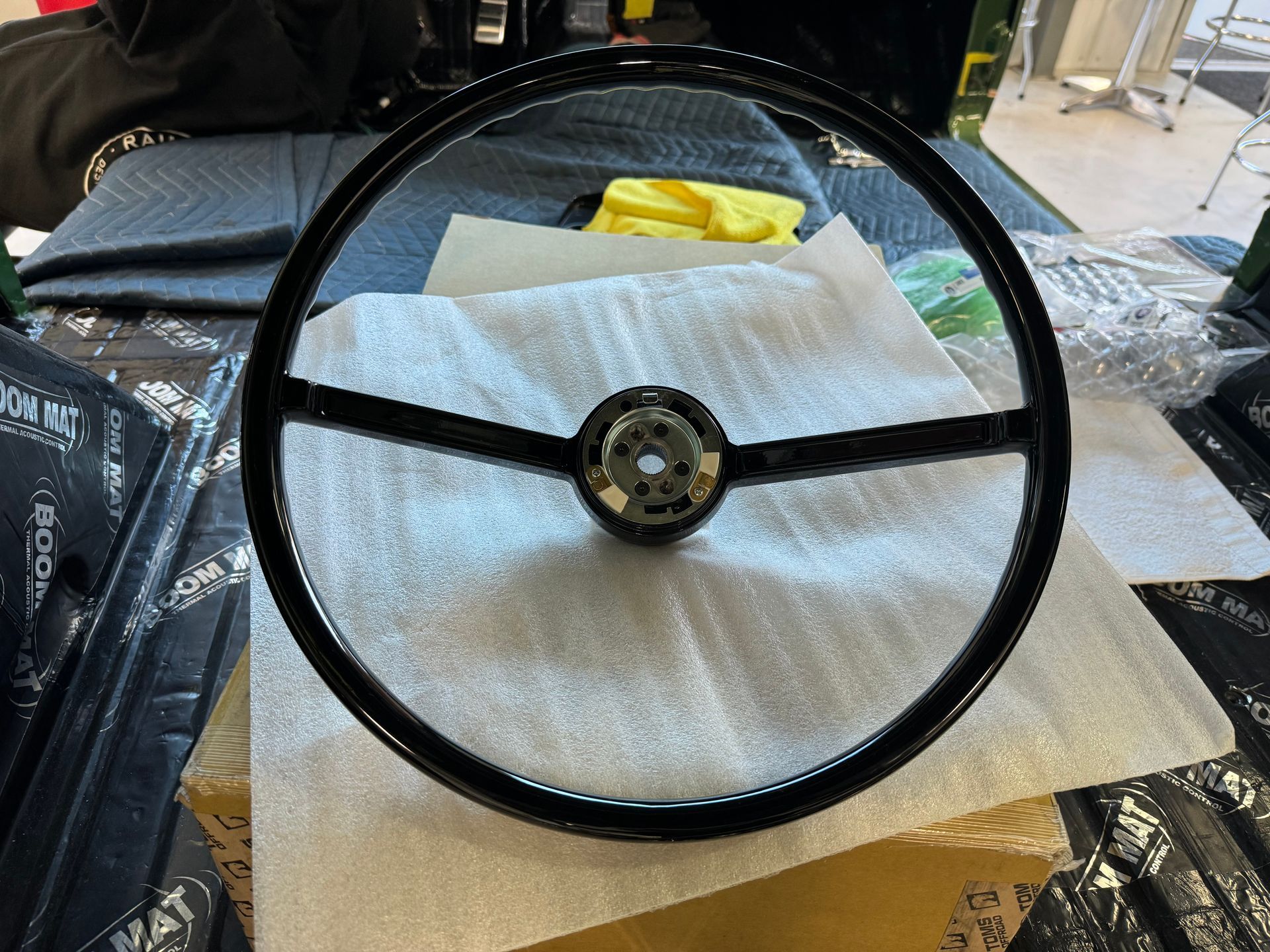 Black steering wheel on white packing foam, with a yellow cloth in the background.