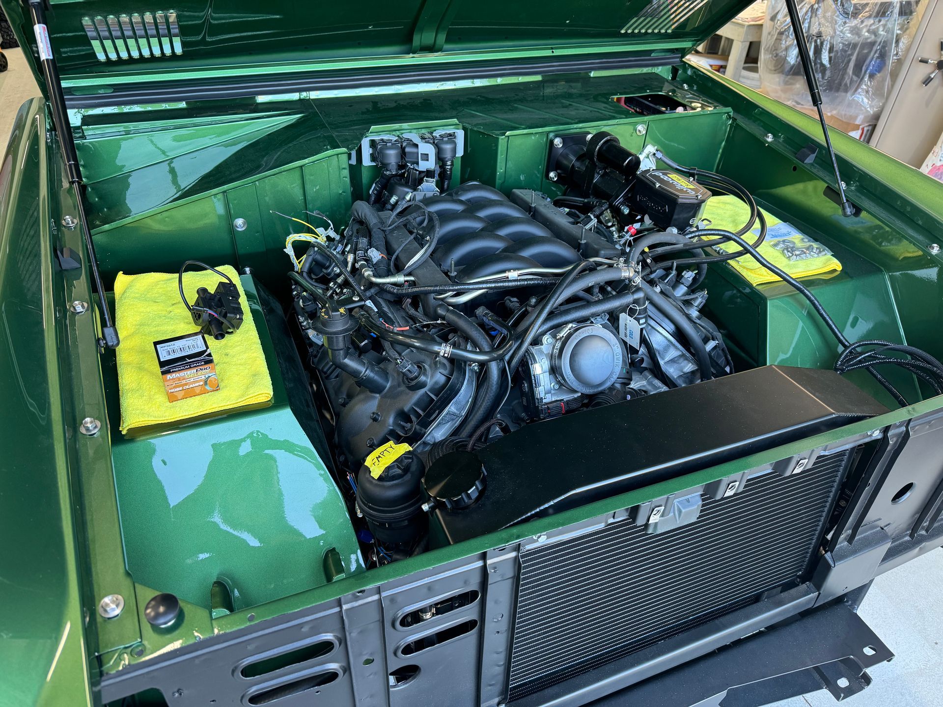 Green car with hood open, showing a detailed engine bay and radiator in the front compartment.
