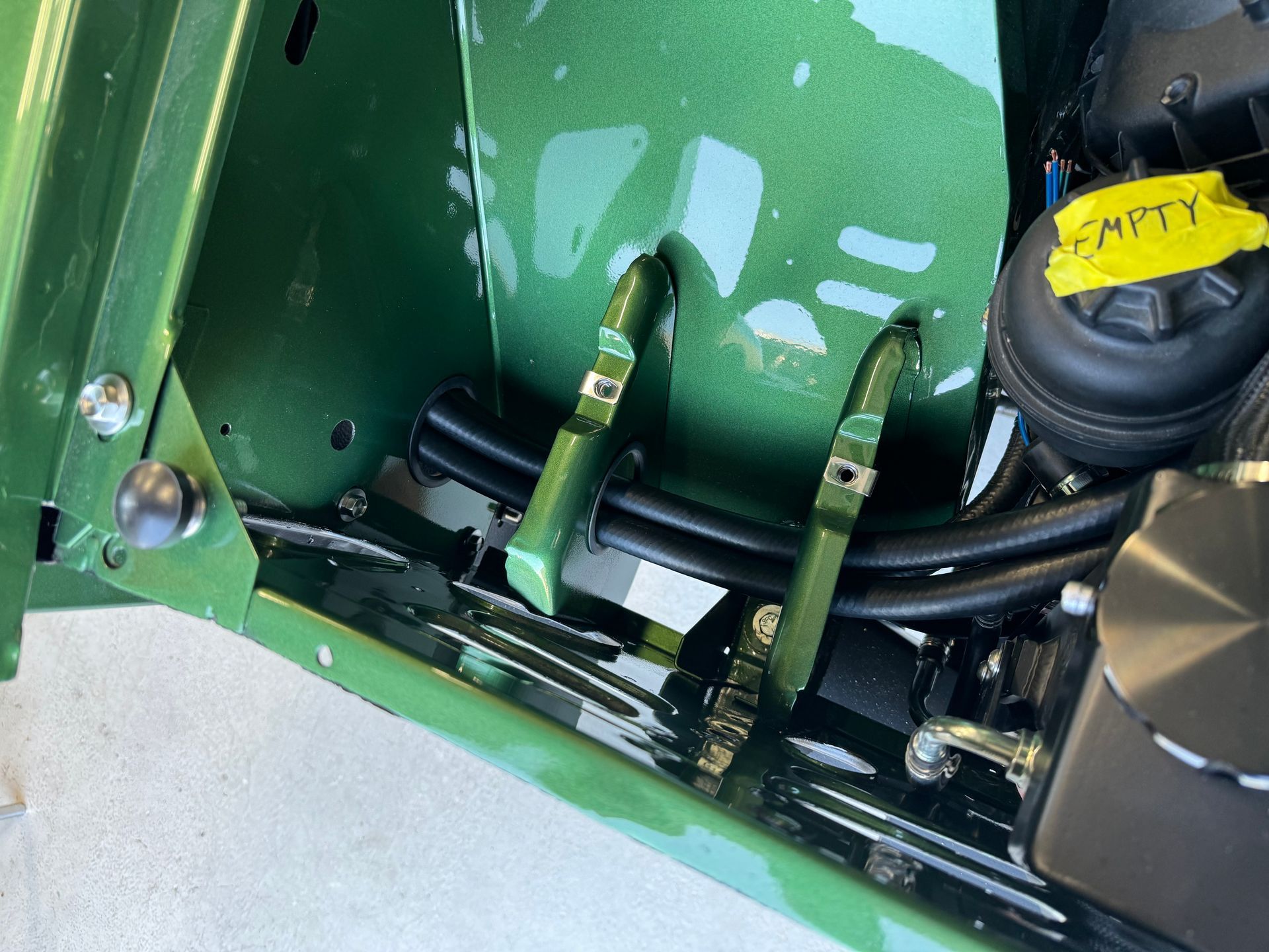 Green machine controls and black fluid cap labeled “EMPTY” in a mechanical compartment