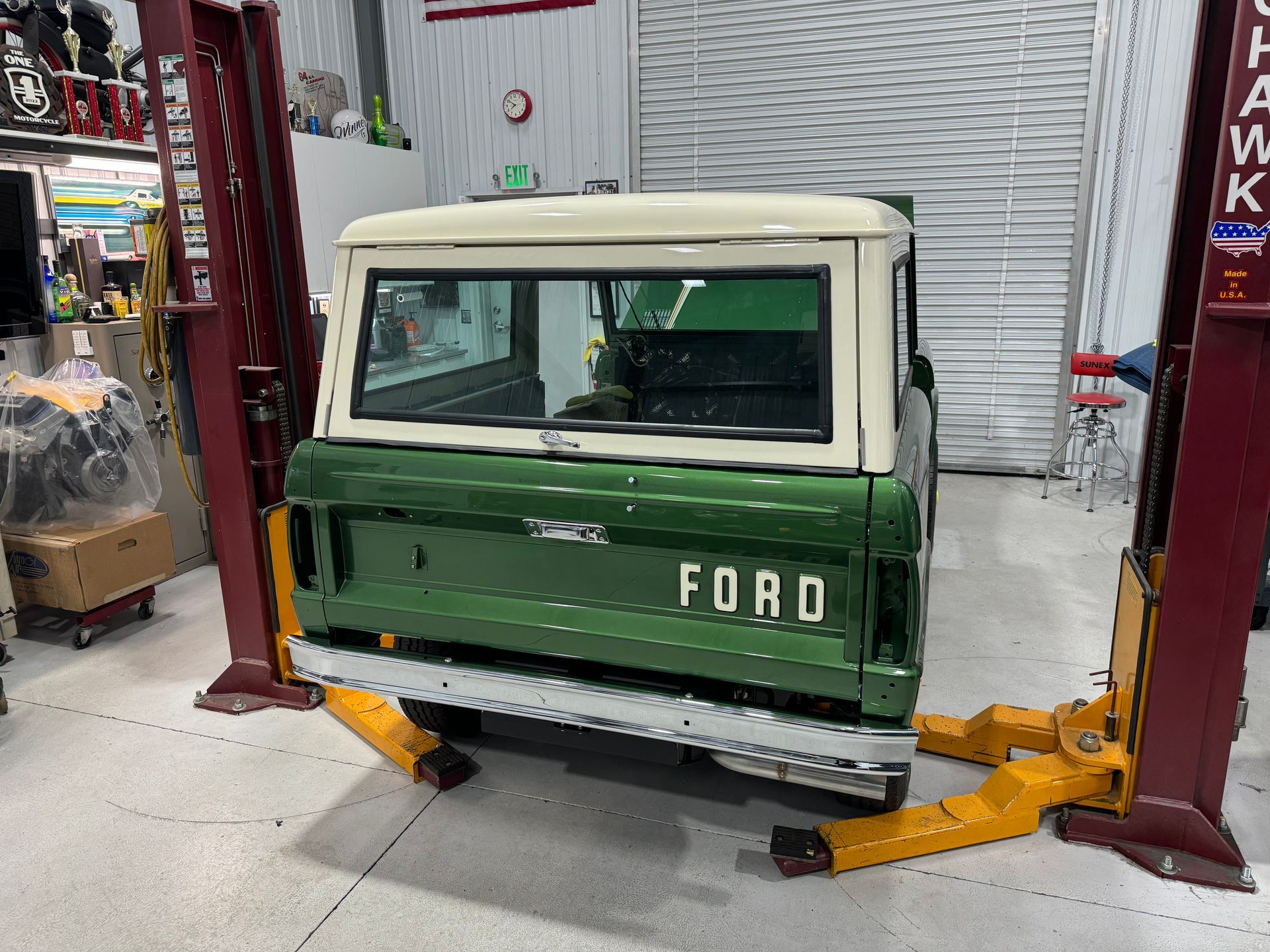 Green Ford pickup truck lifted on a garage hoist in a workshop