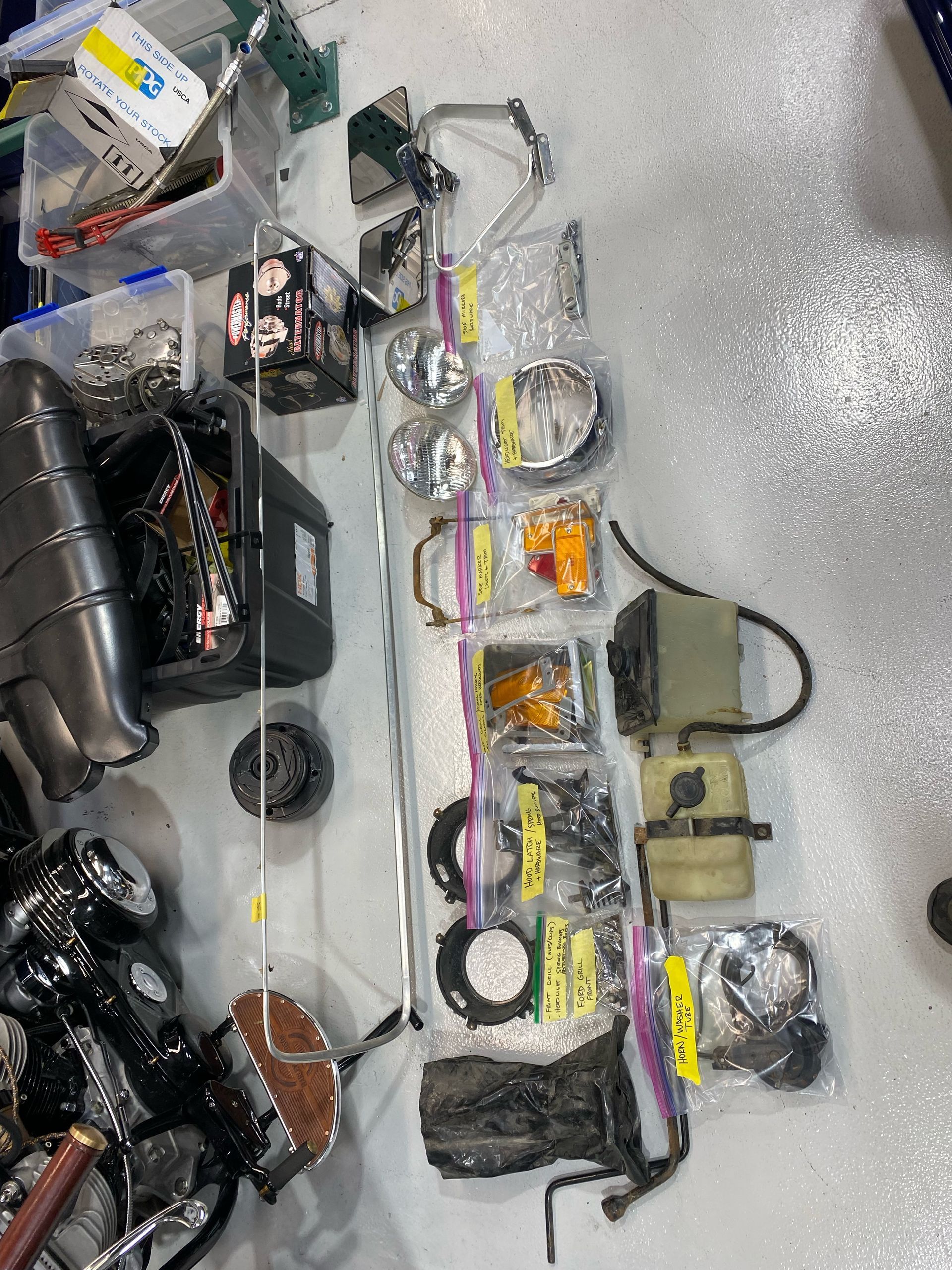 Assorted fishing tackle and gear laid out on the floor, including lures, reels, rods, and bags.