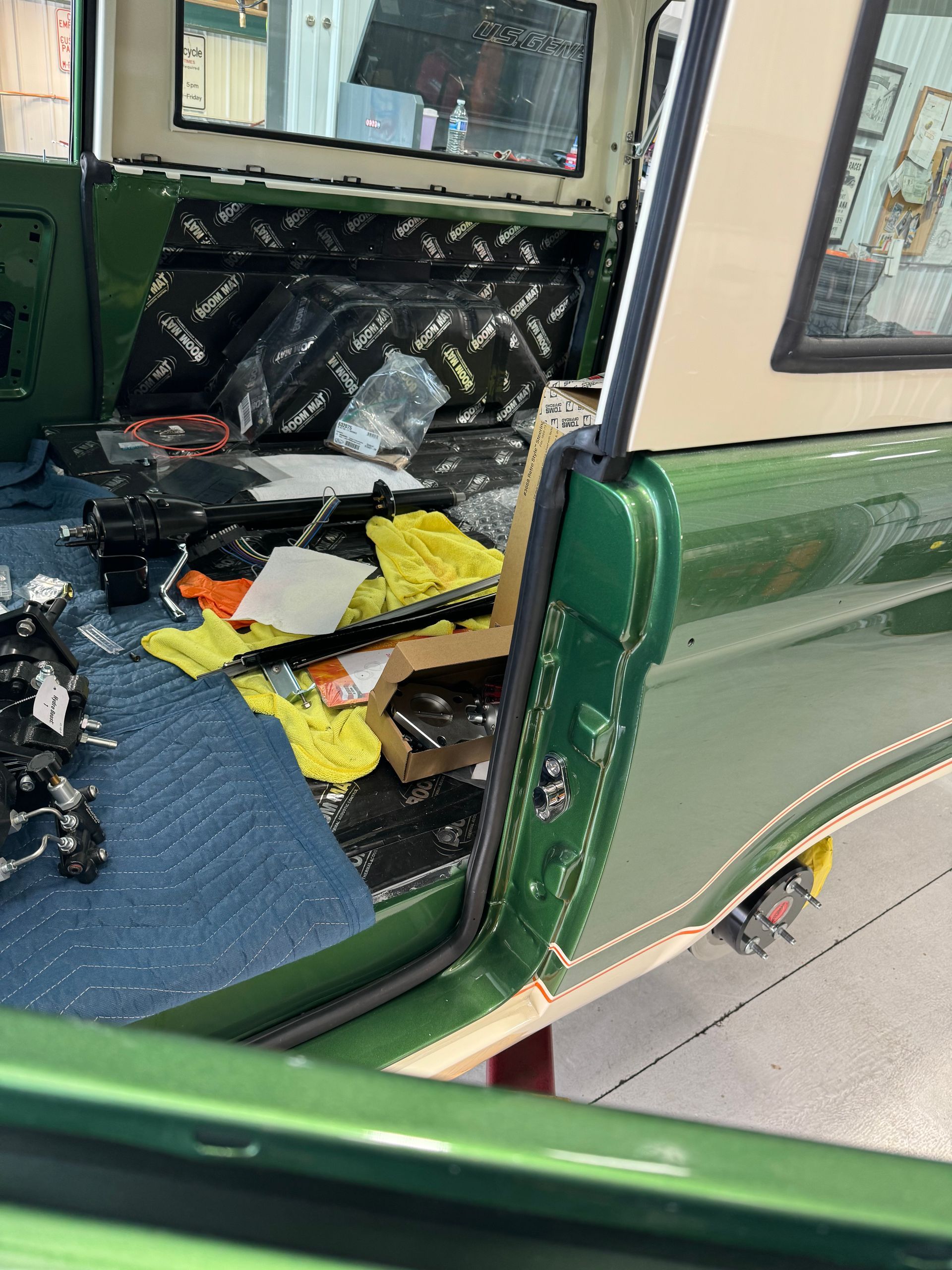 Green vehicle interior with shattered glass, debris, and torn black seats, doors open to the street