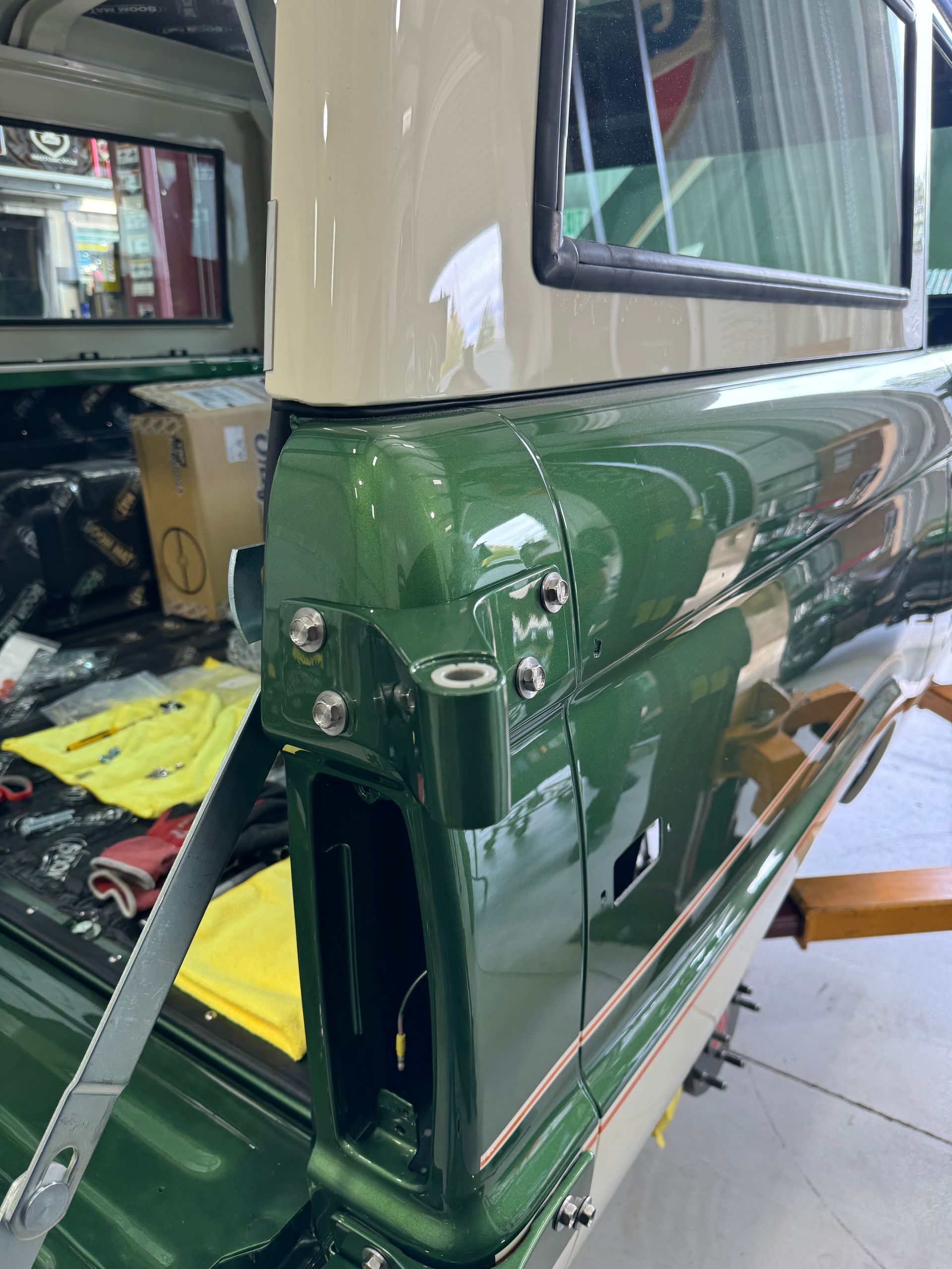Green and cream vintage vehicle body panel in a workshop, with tools and a strap nearby.