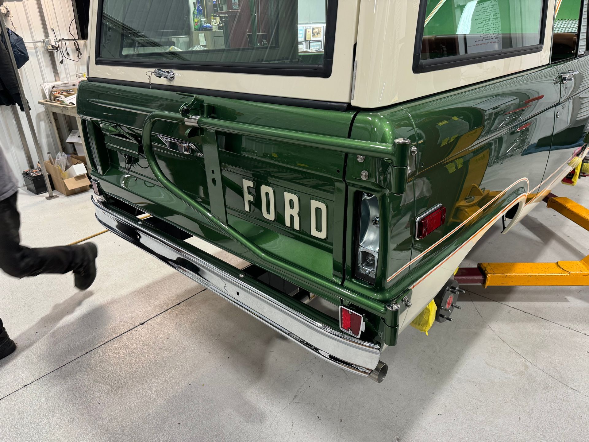 Rear view of a dark green Ford SUV in a garage, showing the tailgate and bumper.